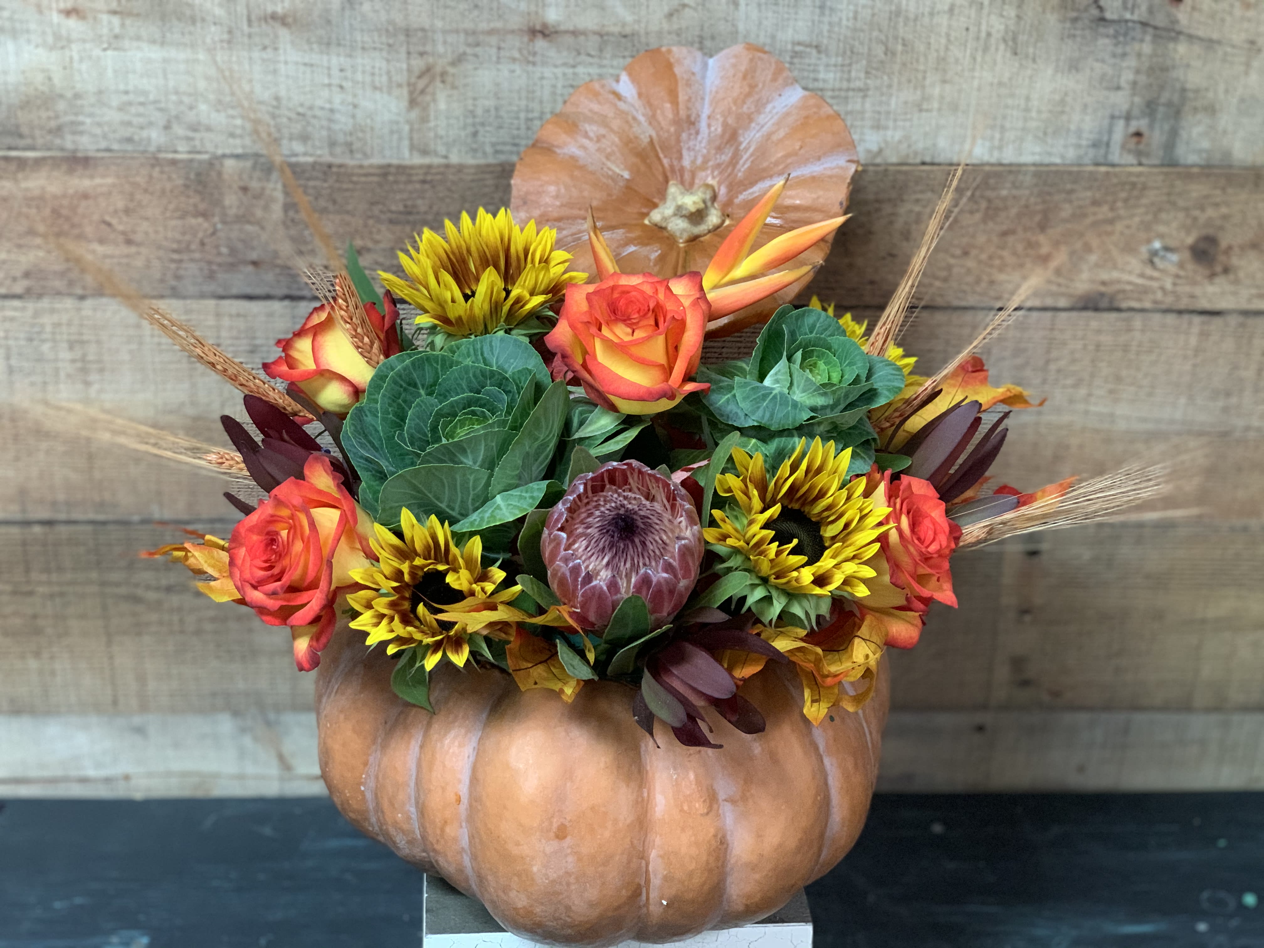 It's the Great Pumpkin - A beautiful Fairy Tale Pumpkin filled with kale, sunflowers, roses, and protea. It makes for a one of a kind gift.  Great for the fall season