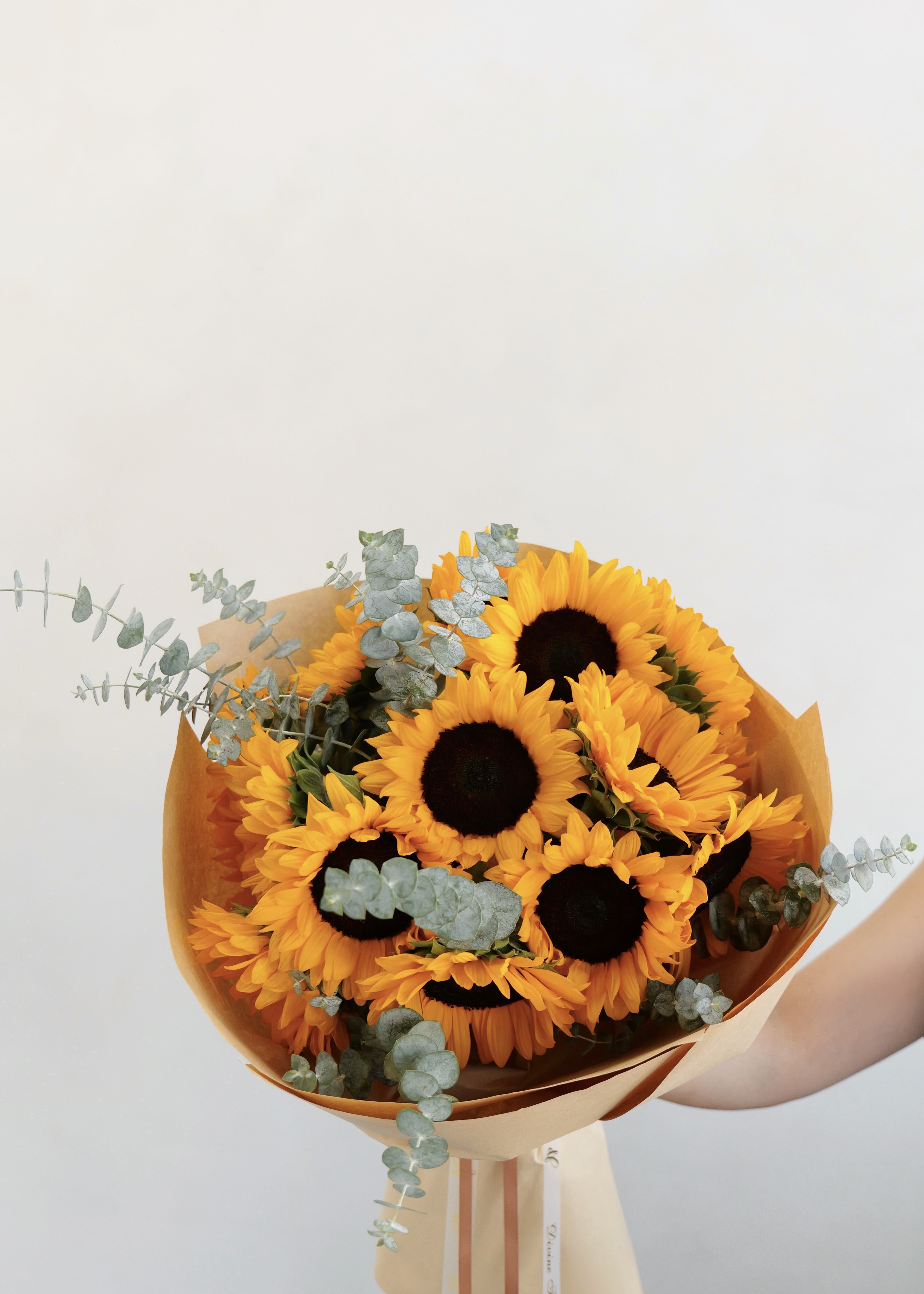 Golden Bloom Golden Bloom - A classic bouquet of fresh sunflowers, beautifully wrapped in soft neutral paper. This timeless arrangement brings warmth, happiness, and natural charm to any space.
