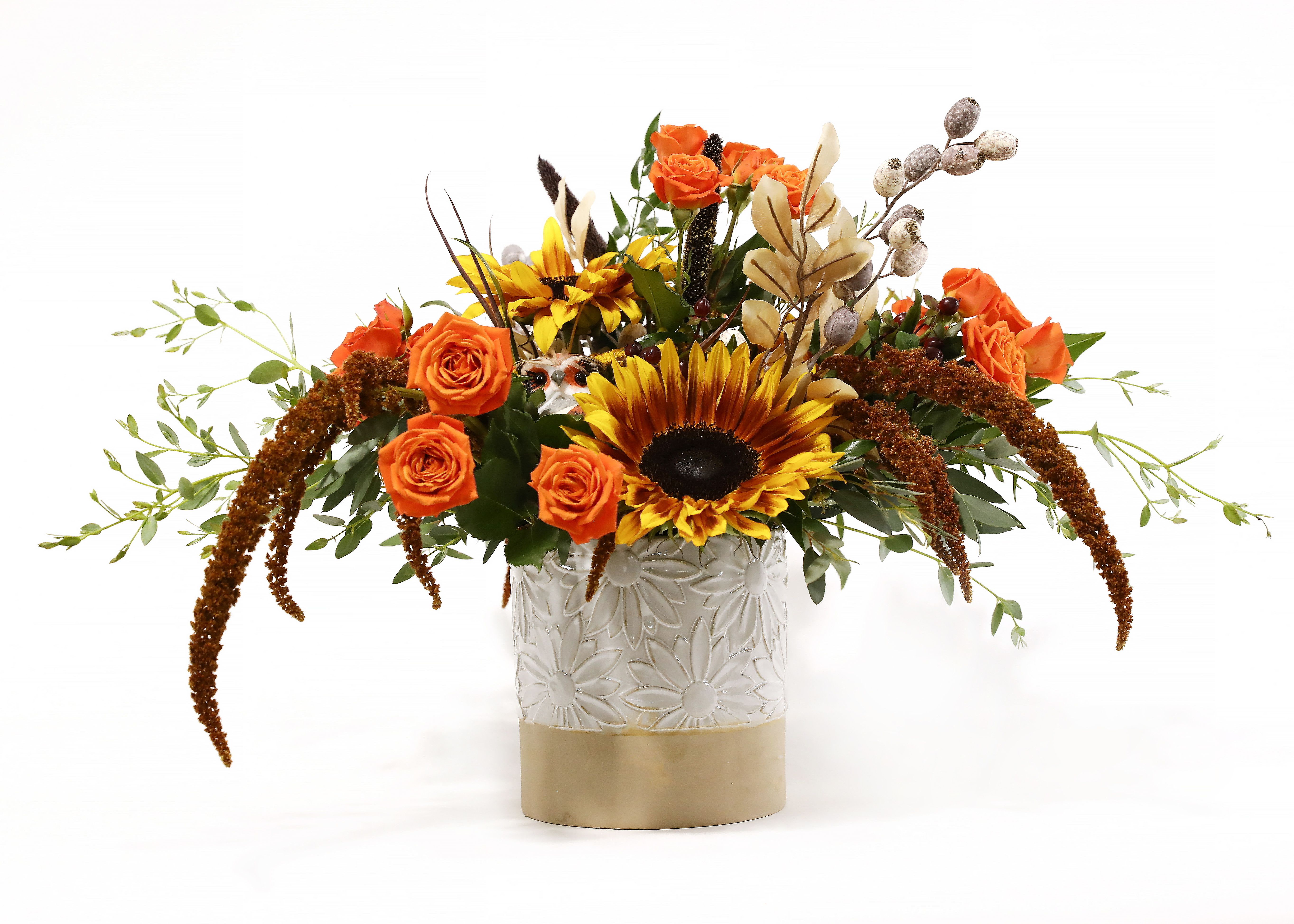 FESTIVE SUNFLOWER FESTIVE SUNFLOWER - THIS WHITE CERAMIC SUNFLOWER IMPRINTED VASE IS TO CUTE TO PASS UP. IT IS SO VERSATILE. THIS FALL THEMED ARRANGEMENT HAS FIRE SUNFLOWERS, SPRAY ROSES, AND MILLET, AMARANTHUS AND FAUX DECORATIONS.