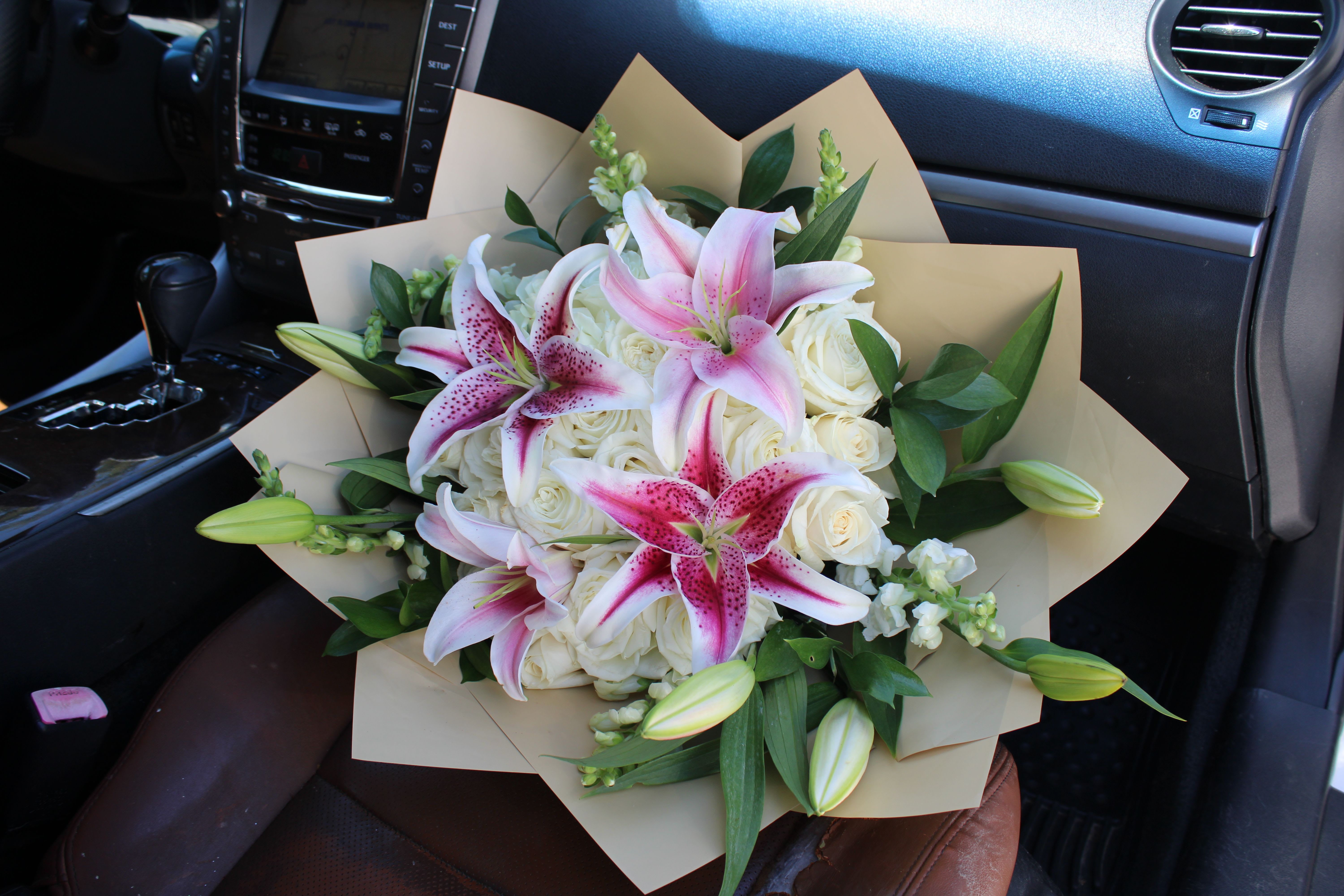 Stargazers - White Roses, Stargazers in the center and on the outer edges. Wrapped in Kraft colored waterproof paper. *NO VASE INCLUDED*