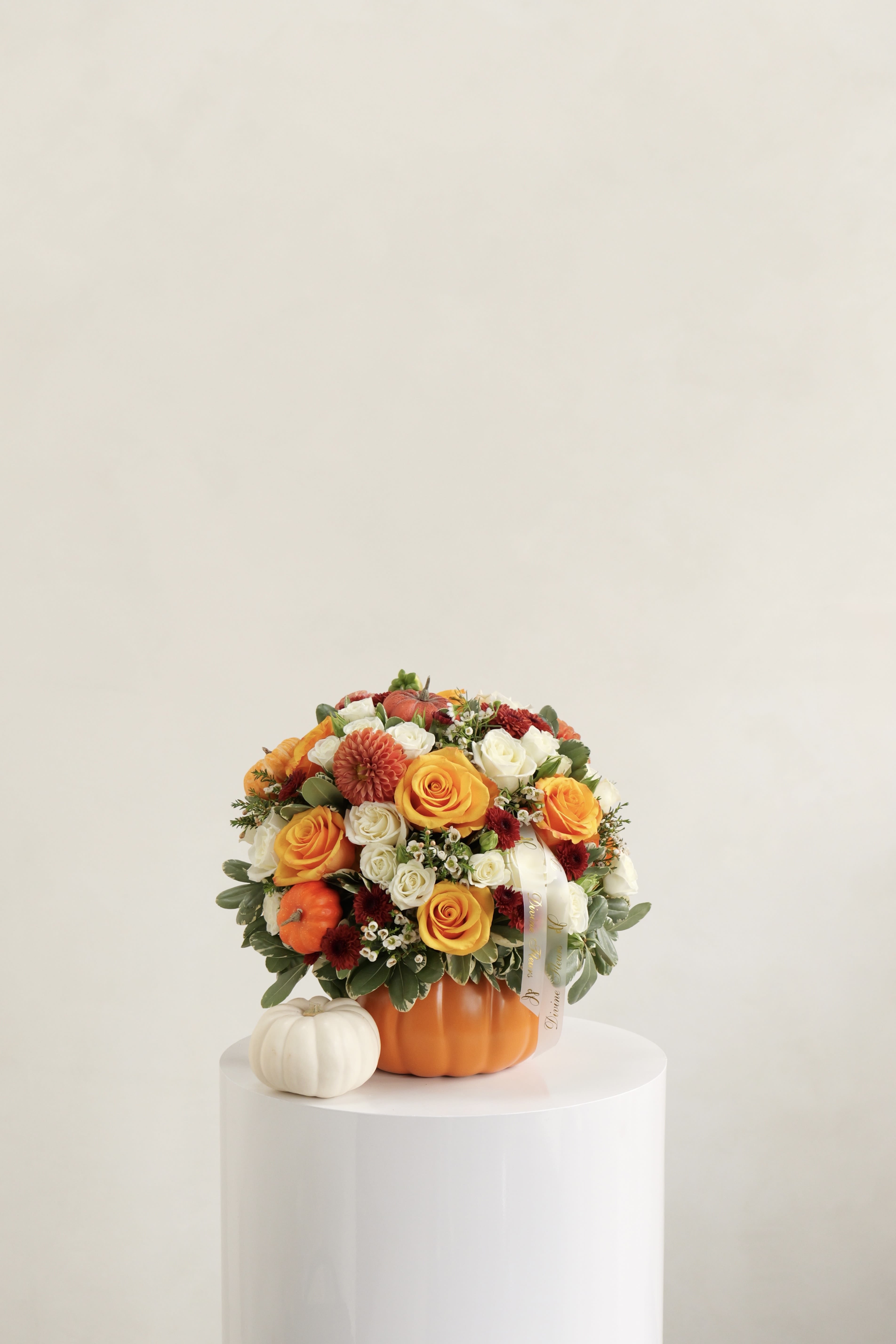 Blooming Pumpkin - Designed in an elegant pumpkin vase, this seasonal arrangement showcases vibrant orange rose, paired with dahlias, and soft accent blooms. Each piece is thoughtfully composed to reflect the cozy glow of autumn, making it an ideal centerpiece or gift for the season.