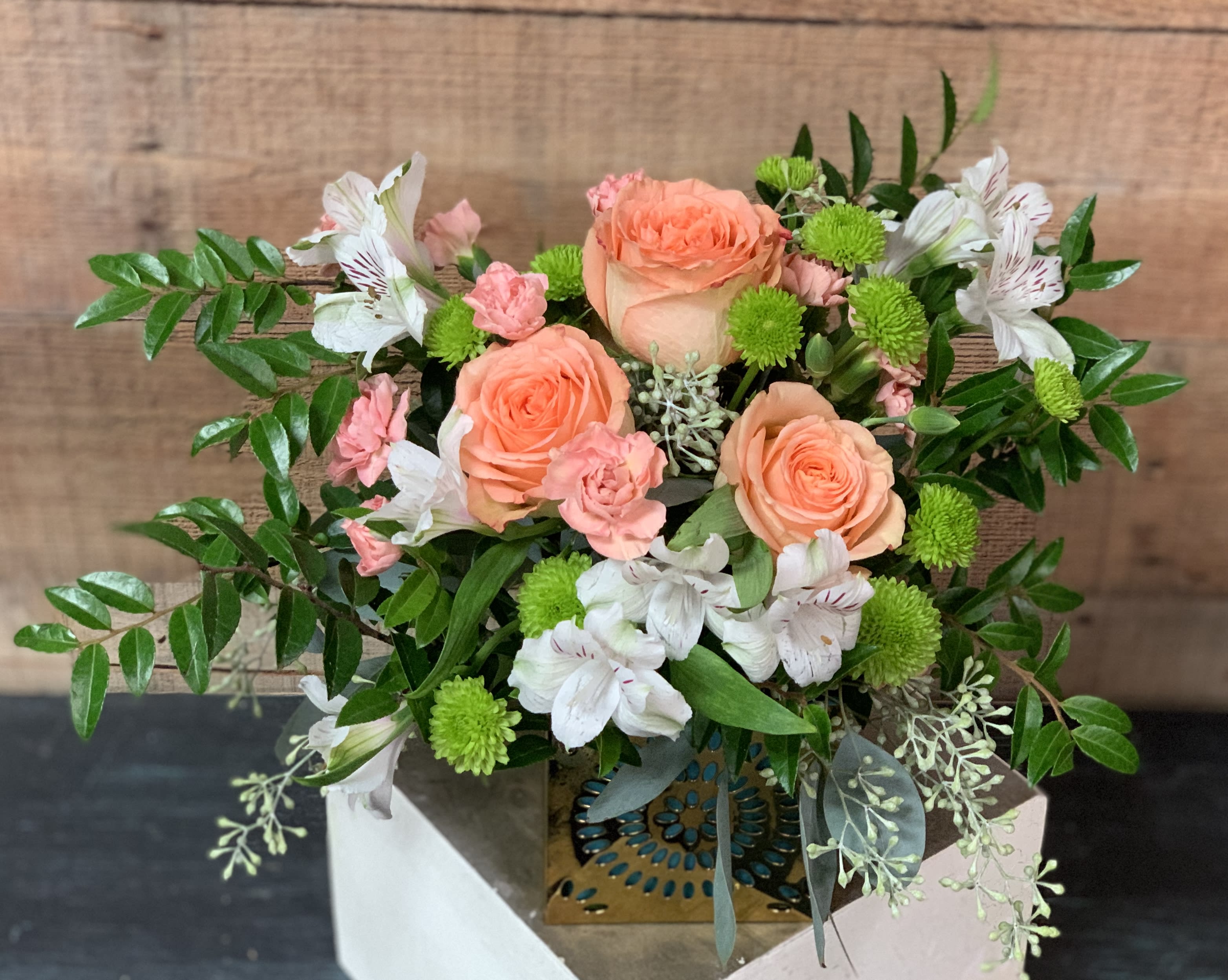 Peach Pleasure - An arrangement of Peach roses, peach mini carnations, and white alstromeria in a golden cube vase