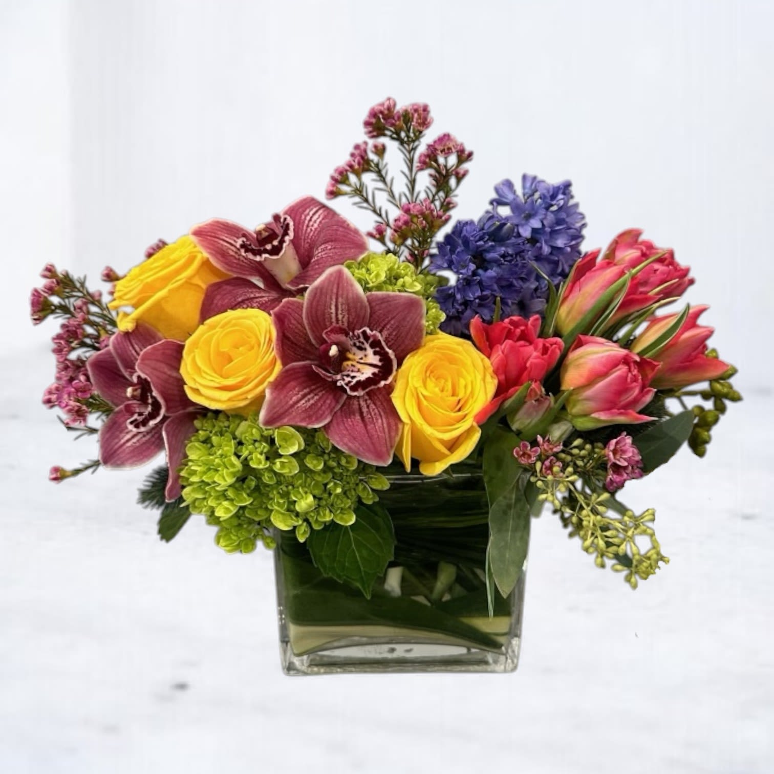 Paintbox Petals Paintbox Petals - Paintbox Petals – Bright Mixed Flower Arrangement with Orchids, Tulips & Hydrangeas Bring a burst of color and creativity to someone’s day with Paintbox Petals. This vibrant floral arrangement features a joyful blend of yellow roses, burgundy cymbidium orchids, vibrant tulips, purple hyacinths, and green hydrangeas — all thoughtfully arranged in a compact modern cube. A true celebration of color and design, Paintbox Petals is perfect for sending congratulations, uplifting a friend, or marking a creative milestone with something unforgettable.