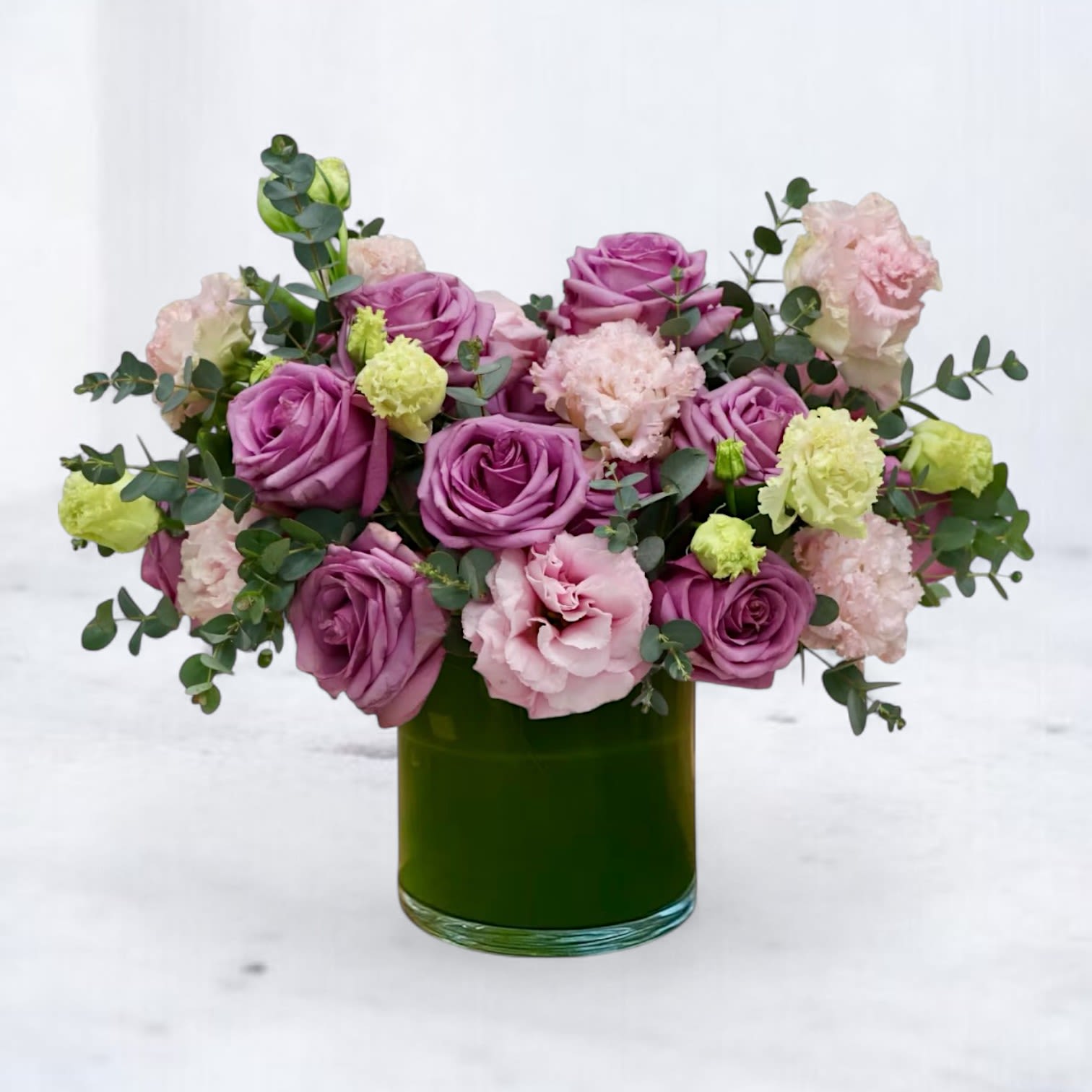 Lavender Harmony Lavender Harmony - Lavender Harmony is a softly structured, modern floral arrangement designed with layered texture and romantic color. Styled in a green glass cylinder vase, this design features lavender roses, blush lisianthus and soft eucalyptus greenery, creating a balanced, modern silhouette with gentle movement. Perfect for sympathy flowers, thinking of you gifts, romantic gestures, or elegant home décor, Lavender Harmony delivers quiet luxury with a lush, elevated palette. Same-day flower delivery available in Houston, Magnolia, Tomball, Cypress and the surrounding areas.