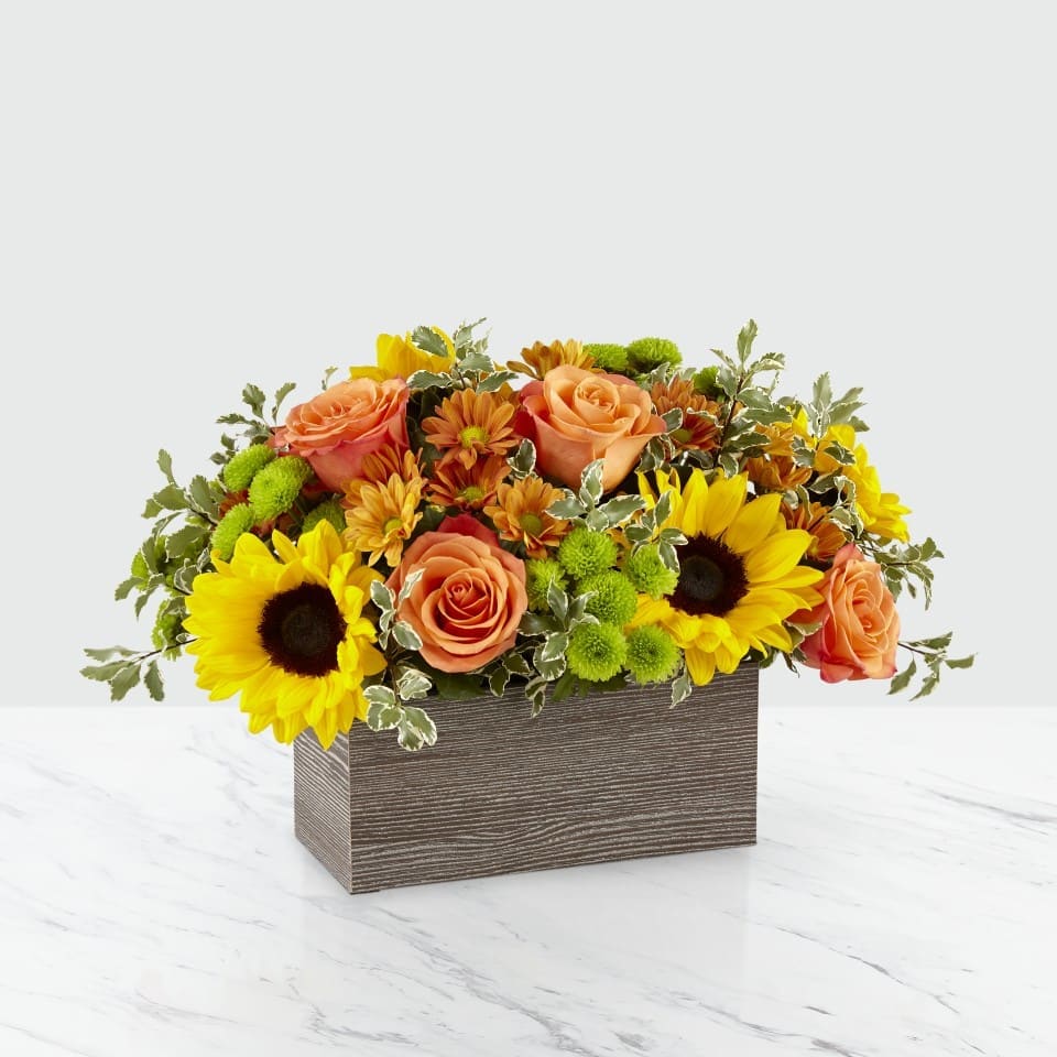 Autumn Harvest Autumn Harvest - Spice up your Thanksgiving table with this beautiful centerpiece. Sunny Sunflowers, Orange Roses, Butterscotch Daisy, Gorgeous Green Button Mums with assorted greens will bring a smile to everyone's face.