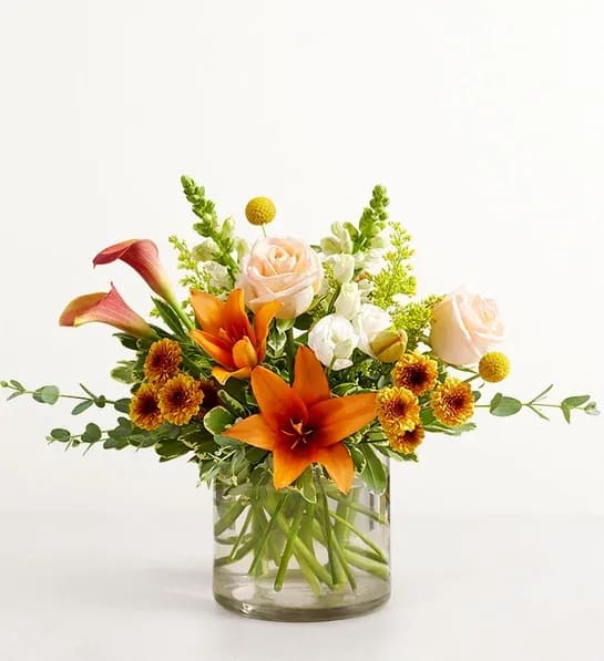 Autumn Amazement Bouquet - Our bouquet captures all the colors and textures of an autumn garden. Highlighted by unique yellow craspedia set among orange, peach, bronze, and white blooms, this loosely gathered arrangement arrives in a glass vase to brighten every gathering and any day.