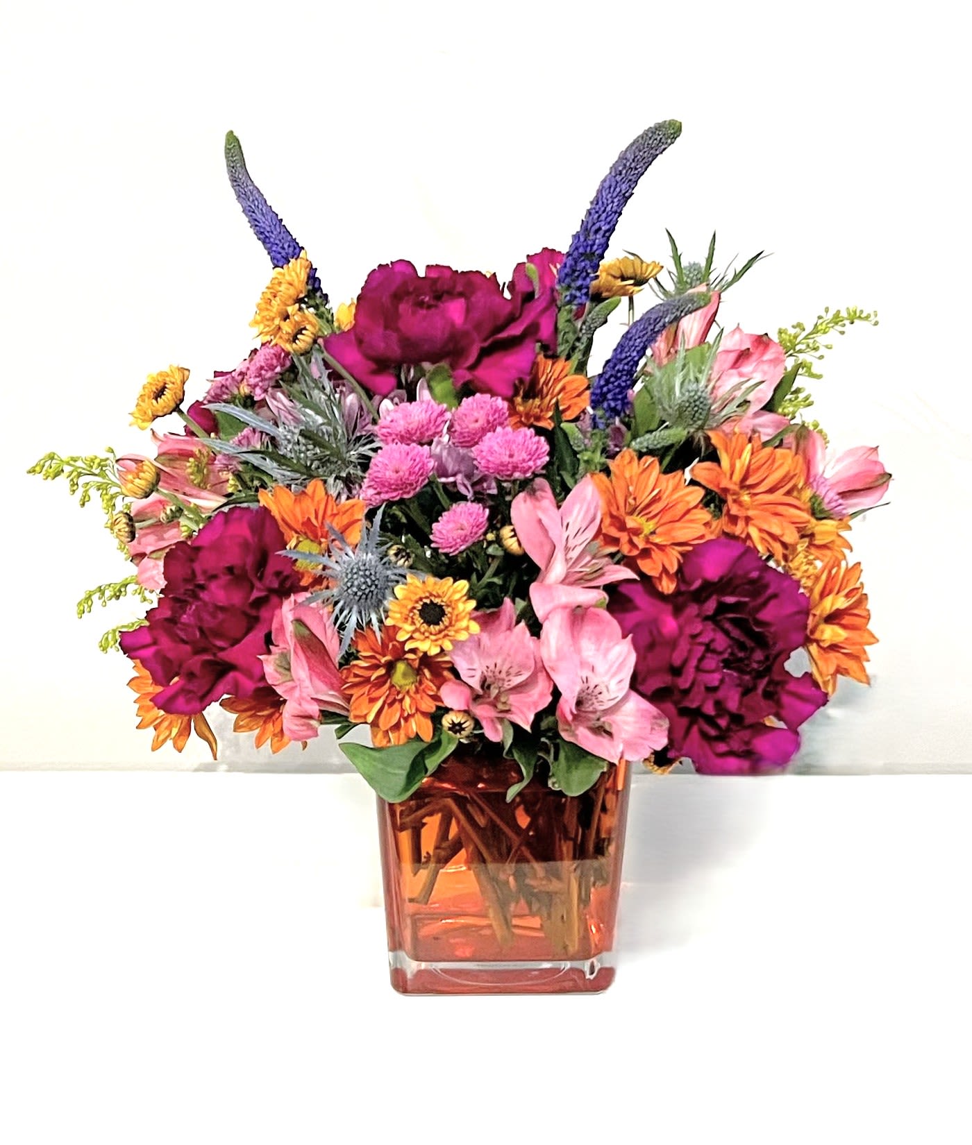 Trick Or Treat  - What better way to celebrate Halloween than with this fun &amp; festive floral gift! A selection of the freshest &amp; spookiest blooms are arranged low and compact &amp; delivered in an orange glass cube.   Measures approx. 12&quot; tall and 12&quot; wide Orientation: All around