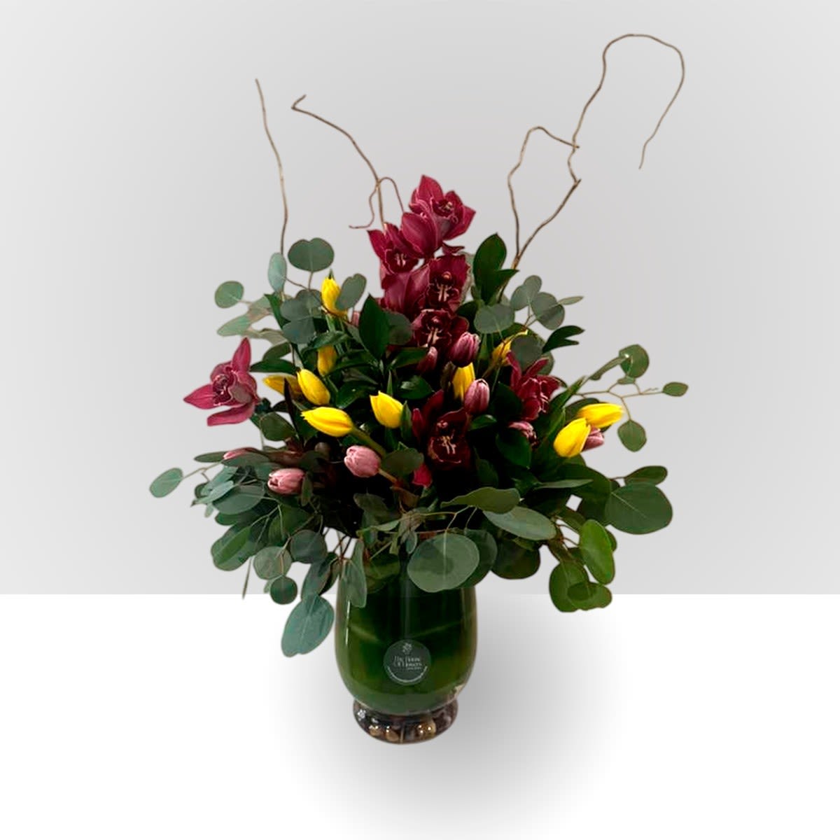 Joy Arrangement by The House of Flowers - Send a selection of tulips and orchids to welcome someone you care about. Always treasured and cherished, orchids have a lot of magic and unparalleled color and are loved by everyone, making them a favorite for that special someone. They are also a great choice for celebrating a birthday or just because at any time of the year, with a tall vase and stones. 