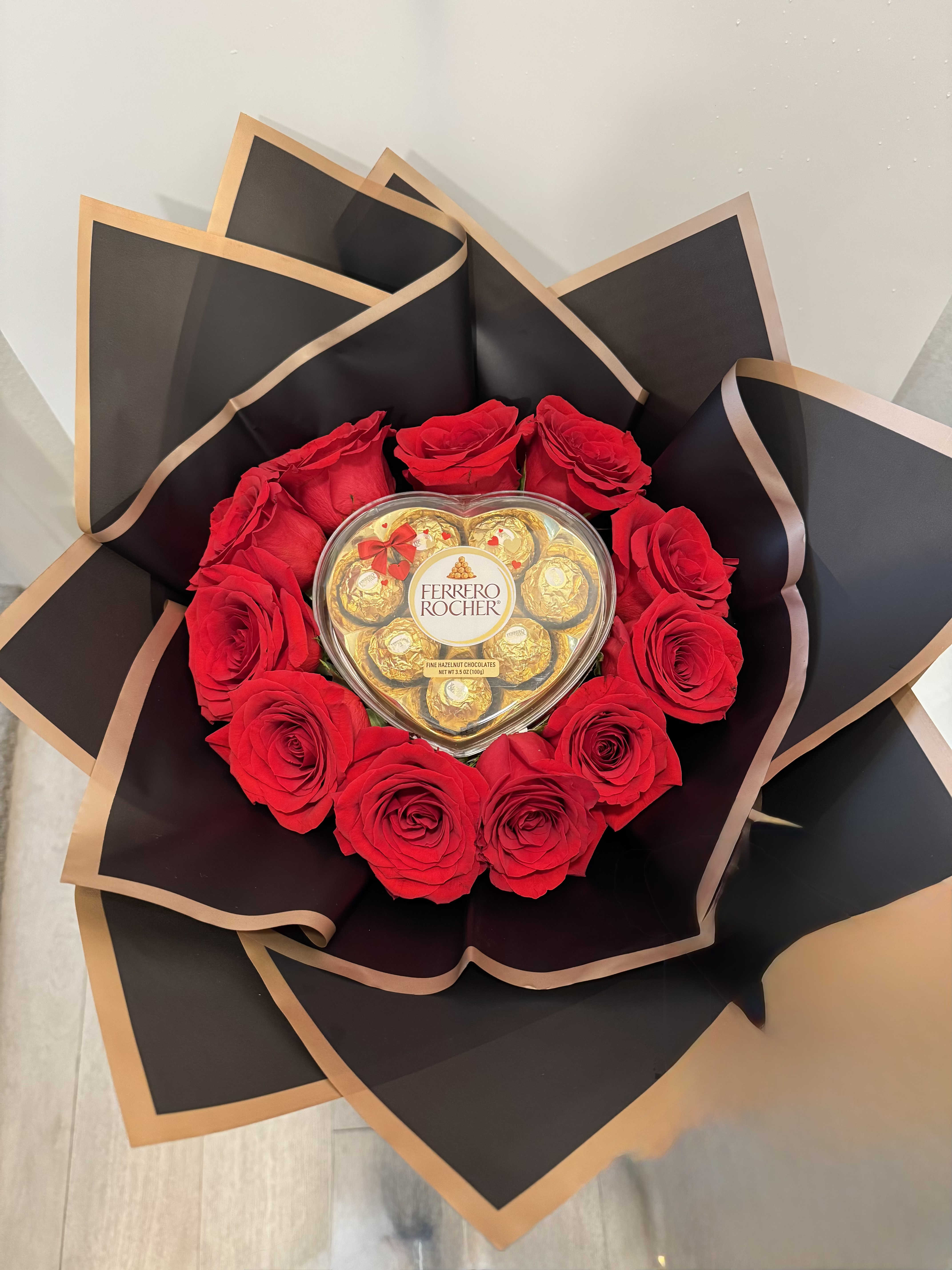 Buchon y ferreros  - Bouquet with red roses around a heart - shaped box of chocolates on a beautiful black paper 