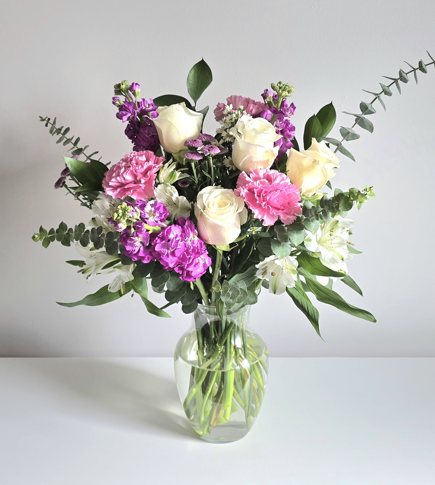 Spring Fling  - This lovely bouquet is full of fragrant stock, roses, eucalyptus, monte casino, long lasting pink carnations, white alstroemeria &amp; greenery. Arranged tall &amp; delivered in a clear glass rose vase. Perfect for sending get well or birthday wishes to friends &amp; loved ones.     APPROXIMATE DIMENSIONS: 12&quot; H X 12&quot; W