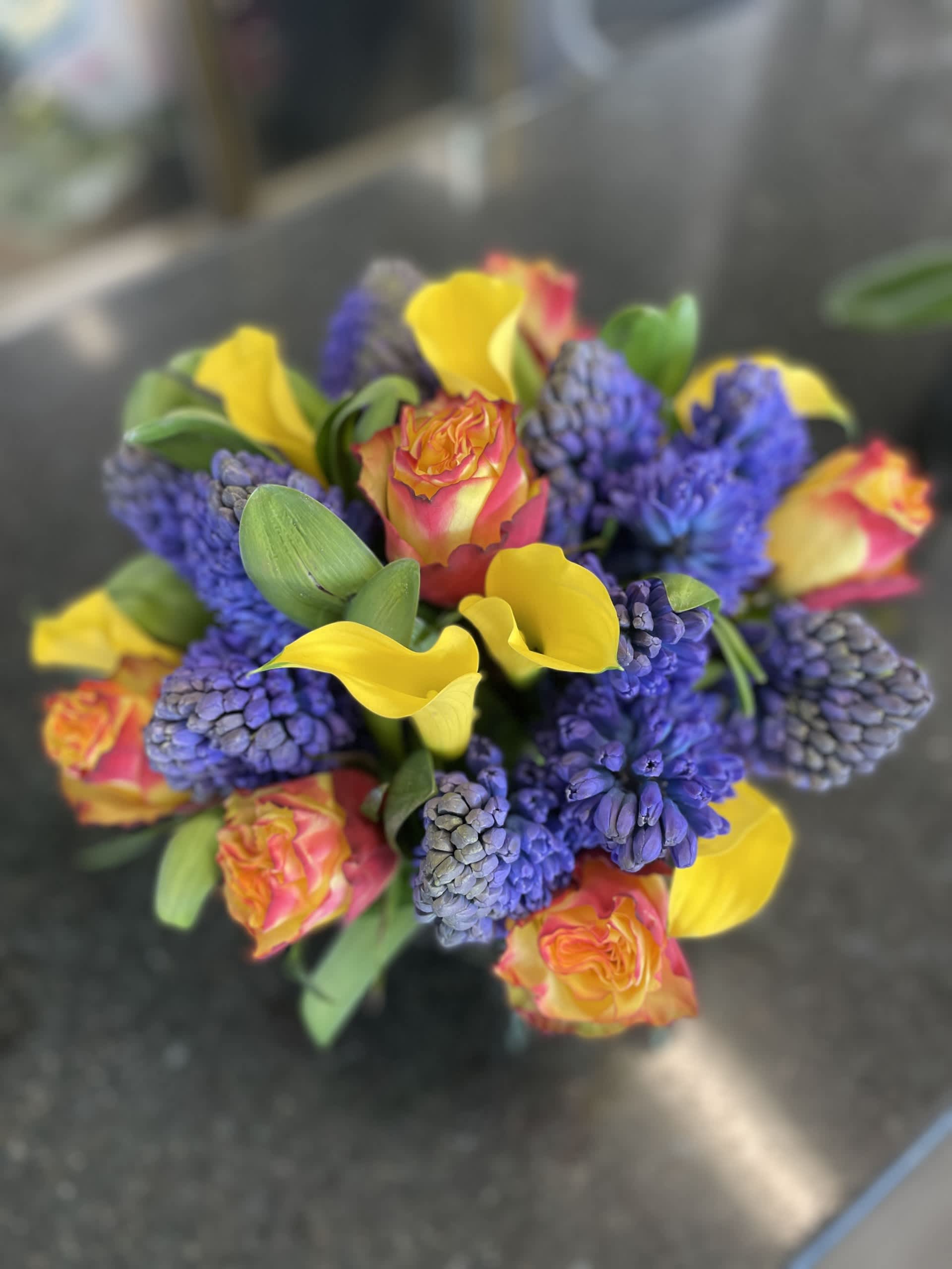 Hyacinth and Sunshine - Medium / Large table arrangement of Blue Hyacinth and Mixture of Yellow Callas and bi colored Roses arranged in a 6 X 6 Glass Cube