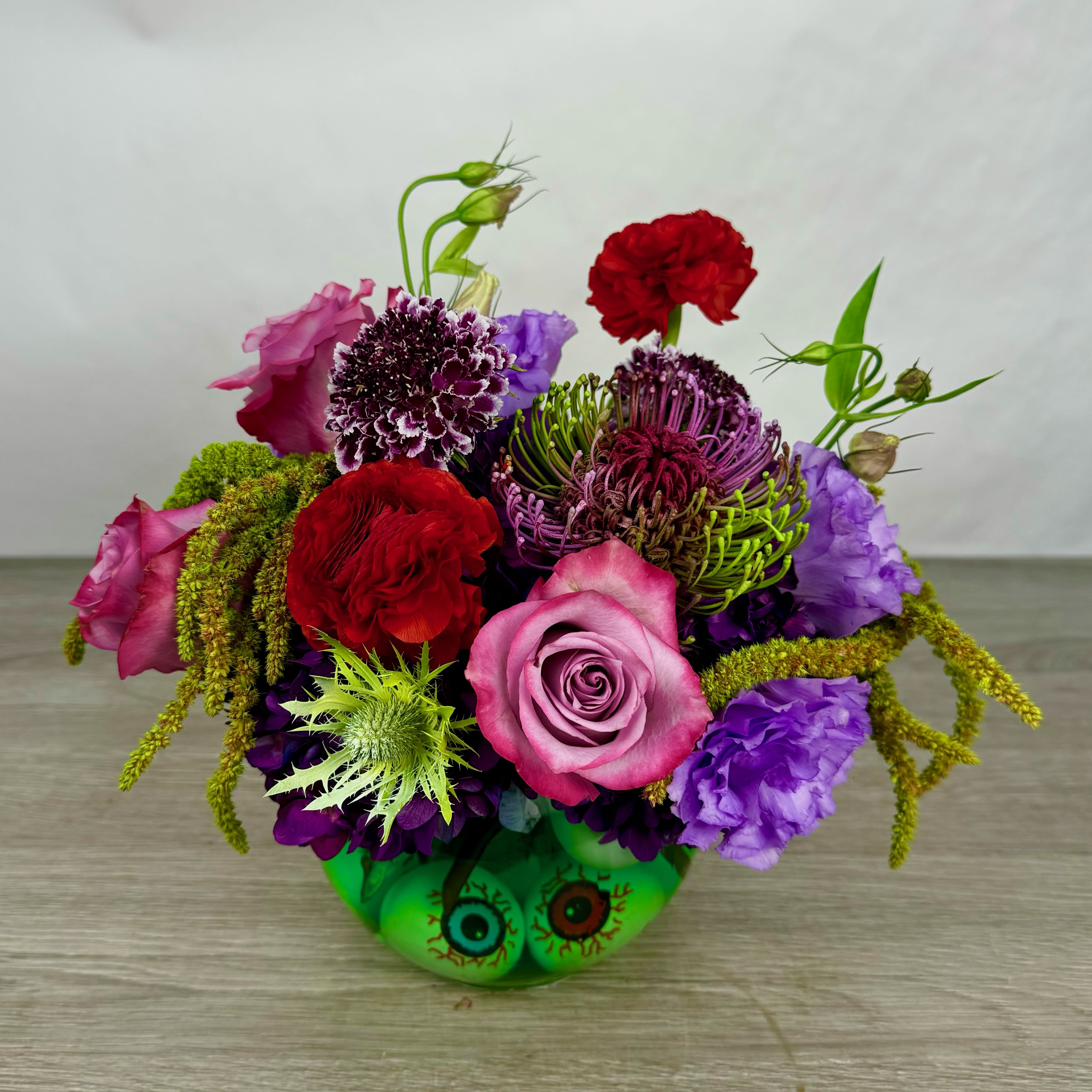 Twitches  - Double, double toil and trouble...This bewitching bouquet is straight from a witch's lair! Nestled in a cauldron-like vase filled with eerie floating eyeballs, this magical arrangement stirs together a spellbinding mix of blooms. Perfect for a Halloween centerpiece or a gift for your favorite witch, this arrangement is a feast for the eyes... literally.