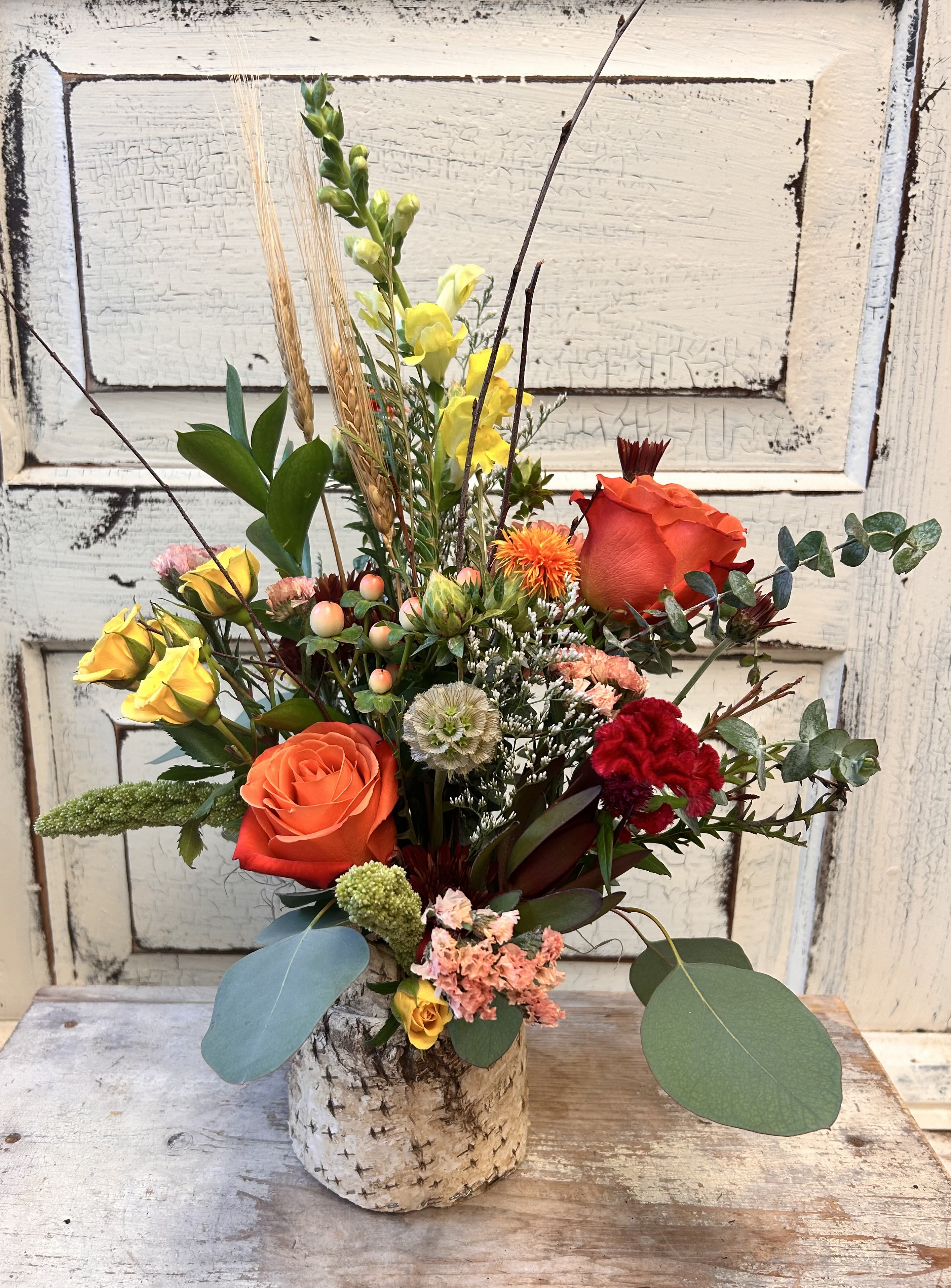 Birch Wrapped Vase - A mini glass vase is nestled inside a birch bark sleeve for a rustic look. This seasonal design will have an assortment of flowers and foliage that varies week to week, along with birch tips and dried wheat. 