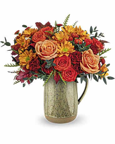 Teleflora's Majestic Meadow Bouquet - Embrace the charm of autumn's majestic meadow with this heartfelt rose bouquet, presented in a stunning stoneware pitcher with a captivating reactive glaze.  This versatile piece is not only a beautiful centerpiece but also a food-safe container, making it ideal for decorating your table on Thanksgiving or any memorable occasion.  This Majestic Meadow Bouquet features vibrant orange roses, spray roses, miniature maroon carnations, rustic brow button spray chrysanthemums, and bronze daisy chrysanthemums, accented with parvifolia eucalyptus and grevillea.  Presented in the Majestic Meadow Pitcher, capturing the autumn's rich hues and natural beauty.