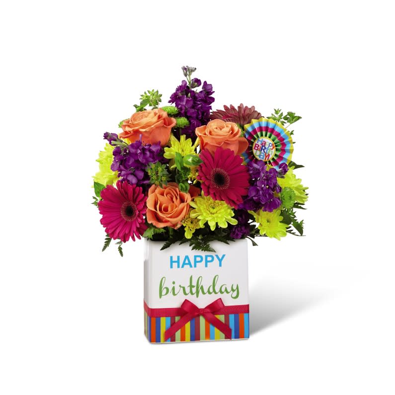 Birthday Brights™ Birthday Brights™ - The Birthday Brights™ Bouquet is a true celebration of color and life to surprise and delight your special recipient on their big day! Hot pink gerbera daisies and orange roses take center stage surrounded by purple statice, yellow cushion poms, green button poms, and lush greens to create party perfect birthday display. Presented in a modern rectangular ceramic vase with colorful striping at the bottom, "Happy Birthday" lettering at the top, and a bright pink bow at the center, this unforgettable fresh flower arrangement is then accented with a striped happy birthday pick to create a fun and festive gift.