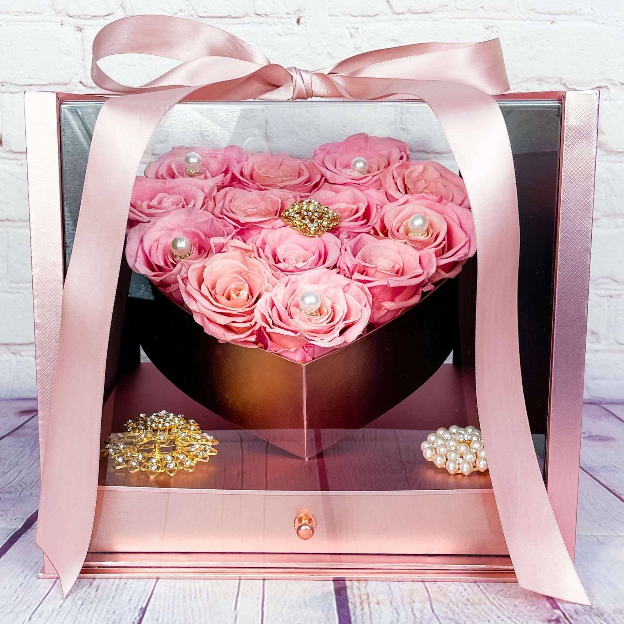 Rose Heart Gift Box - Forever Roses (RED ROSES) - Our Rose Heart Gift Box is a perfect gift for that special someone or this Mother's Day. Inside a stunning see through gift box tied with a matching color bow are 13 stems of Forever roses (Preserved), that last up to 3 years. We make this already beautiful gift even more stunning with accents of pearls and and gold broaches, to create a gift the will never forget.