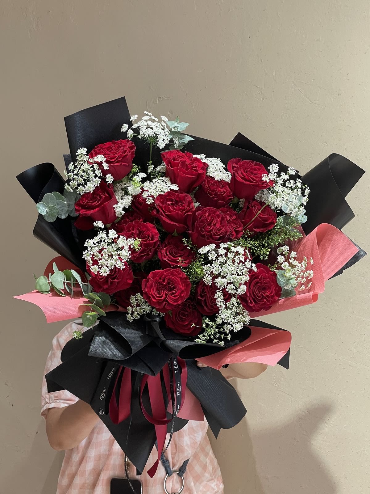 Crimson Desire - The Crimson Desire Bouquet  Say It with Passion, Say It with Love  Presenting the Crimson Desire Bouquet, an exquisite expression of romance and timeless elegance. This captivating arrangement features: 	•	Lush Red Roses: The ultimate symbol of deep love, admiration, and devotion. 	•	Delicate Baby’s Breath: Adding a soft, dreamy touch to complement the bold beauty of the roses. 	•	Elegant Eucalyptus Accents: For a fresh, modern flourish that enhances the bouquet’s charm. 	•	Wrapped in Sophistication: Luxe black and pink wrapping with flowing ribbons for a statement finish.  Perfect for anniversaries, romantic surprises, proposals, or any moment where love deserves to be celebrated.  Let your feelings bloom—gift the Crimson Desire Bouquet and make hearts flutter.