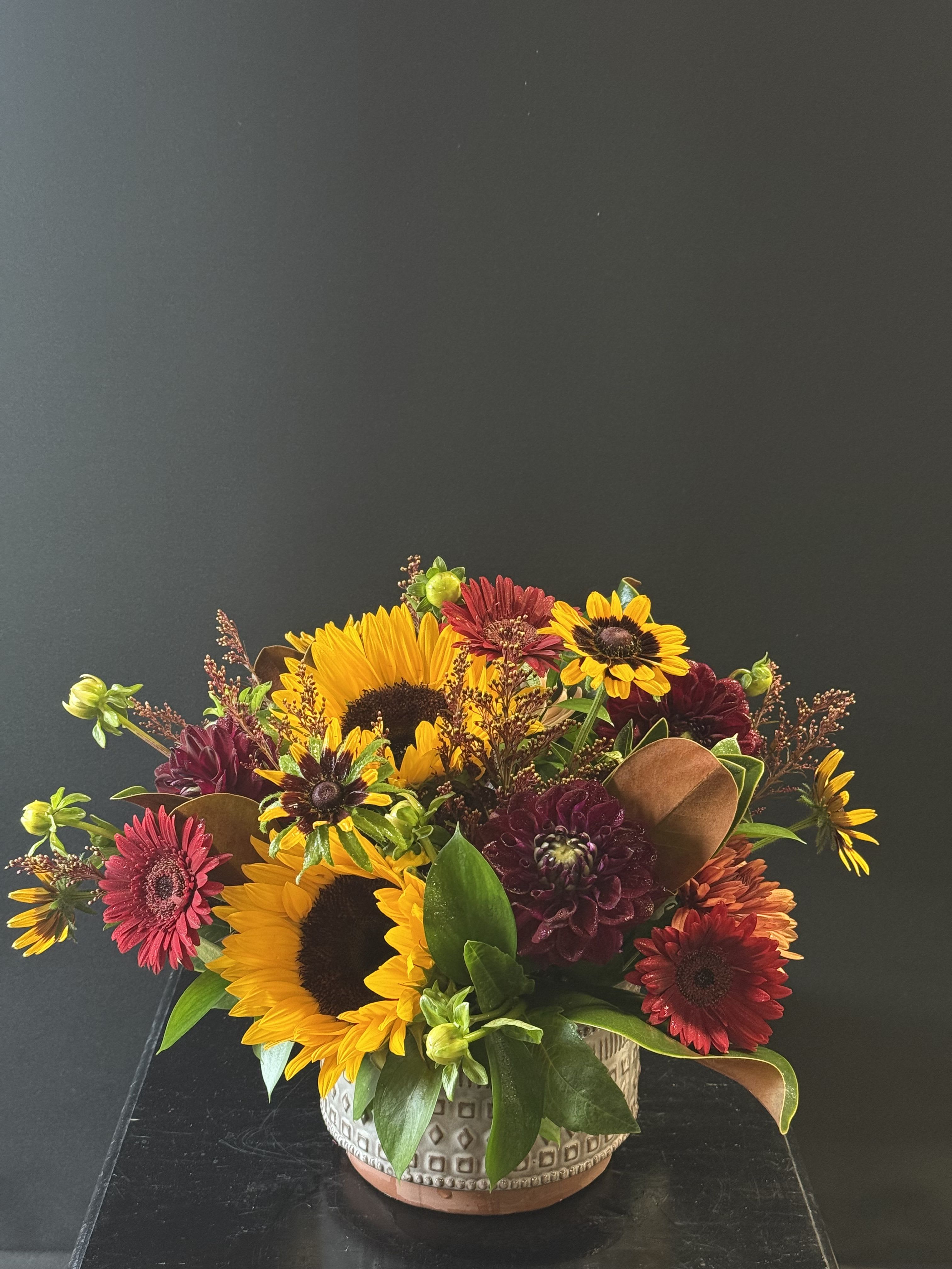Sunset Splendor Sunset Splendor - Sunflowers, dahlias, gerbera daisies, and other fall blooms come together in this cozy, homespun bouquet, bringing warmth of the harvest season into your home.