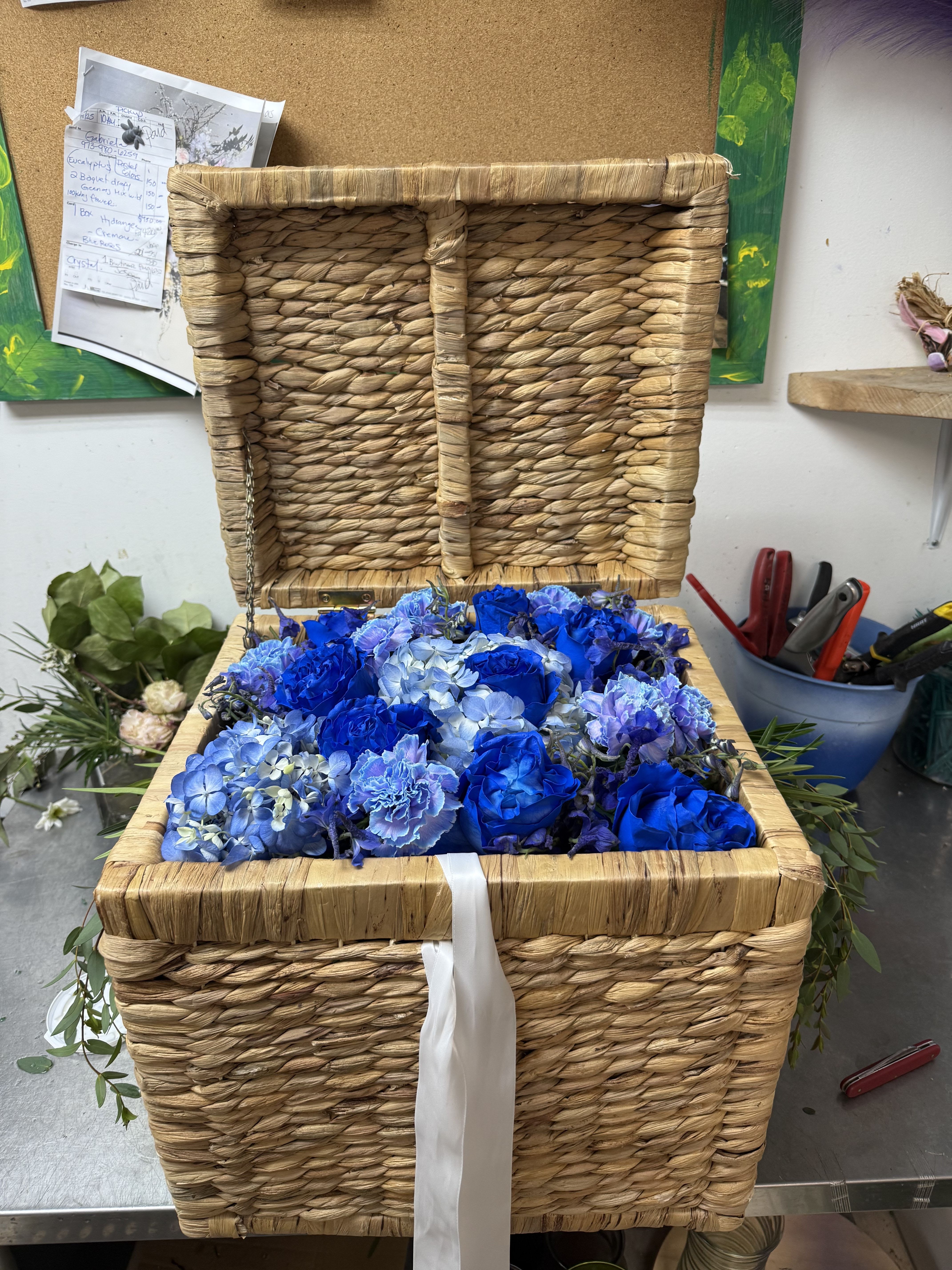 Ocean Treasure Floral Trunk - a handwoven chest brimming with royal blue roses, soft hydrangeas and ruffled carnations, symbolizing depth, loyalty and eternal beauty designed to impress, this floral trunk make a breathtaking gift for a wedding, gender reveal and party center pieces.