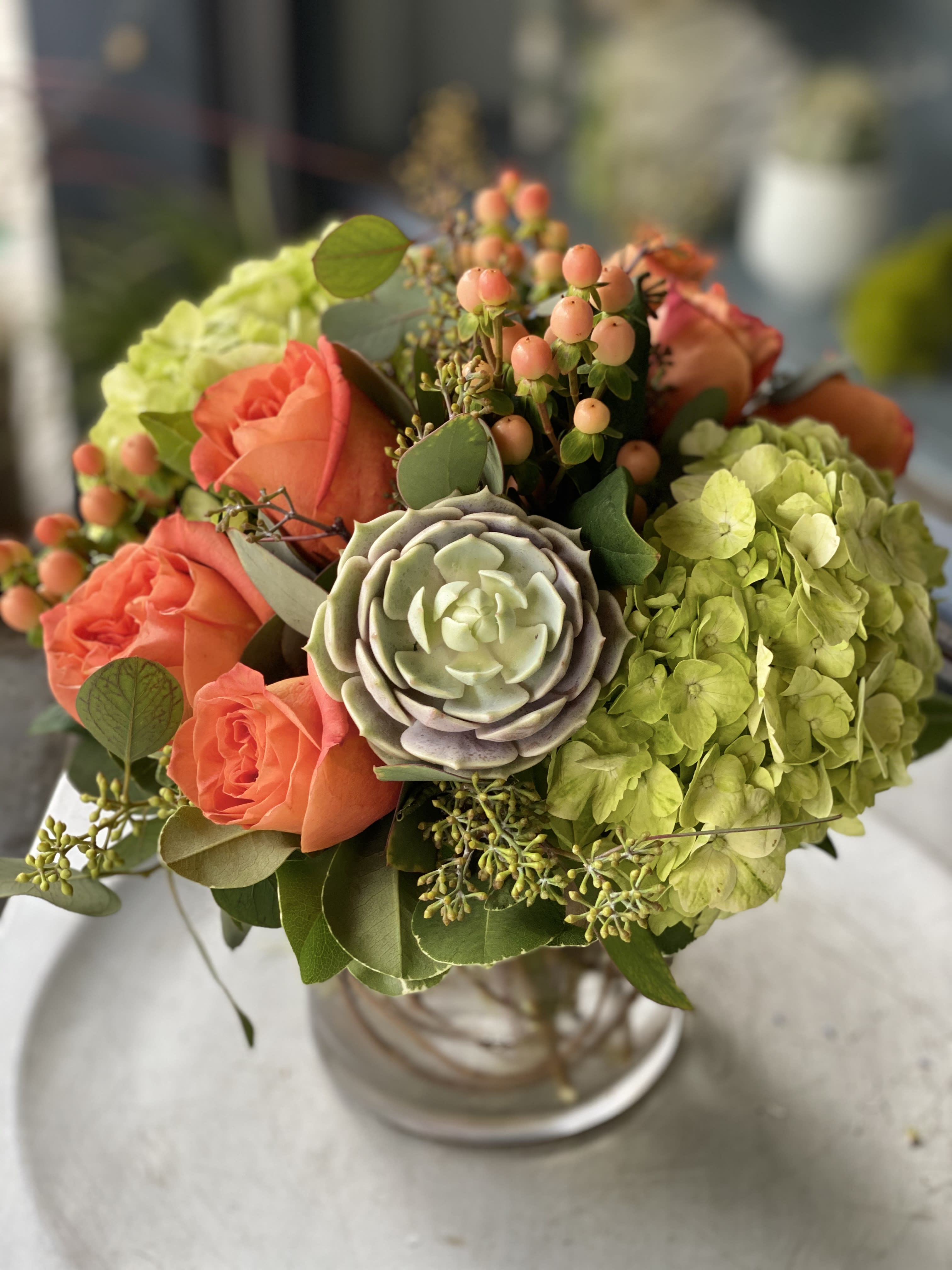 Sunset in San Francisco Sunset in San Francisco - A perfect celebration for any occasion, featuring green hydrangea, kale, succulents and orange roses arranged in a curly willow lined bubble bowl.