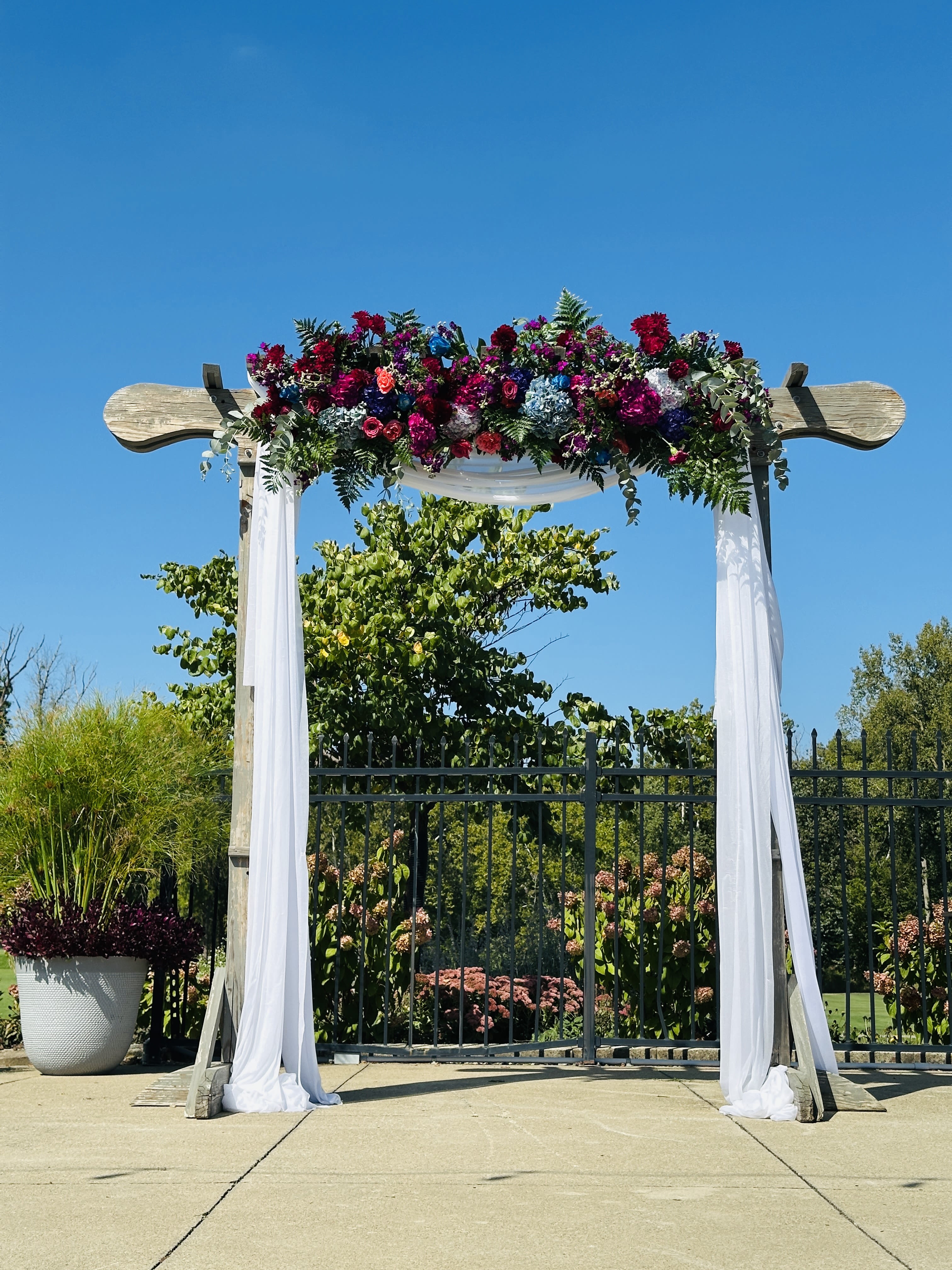Carly wedding arch - Beautiful deep colors of navy blue, burgundy and hot pink/fuchsia colors roses, carnations, daisies, alstroemeria, delphinium and other fillers  