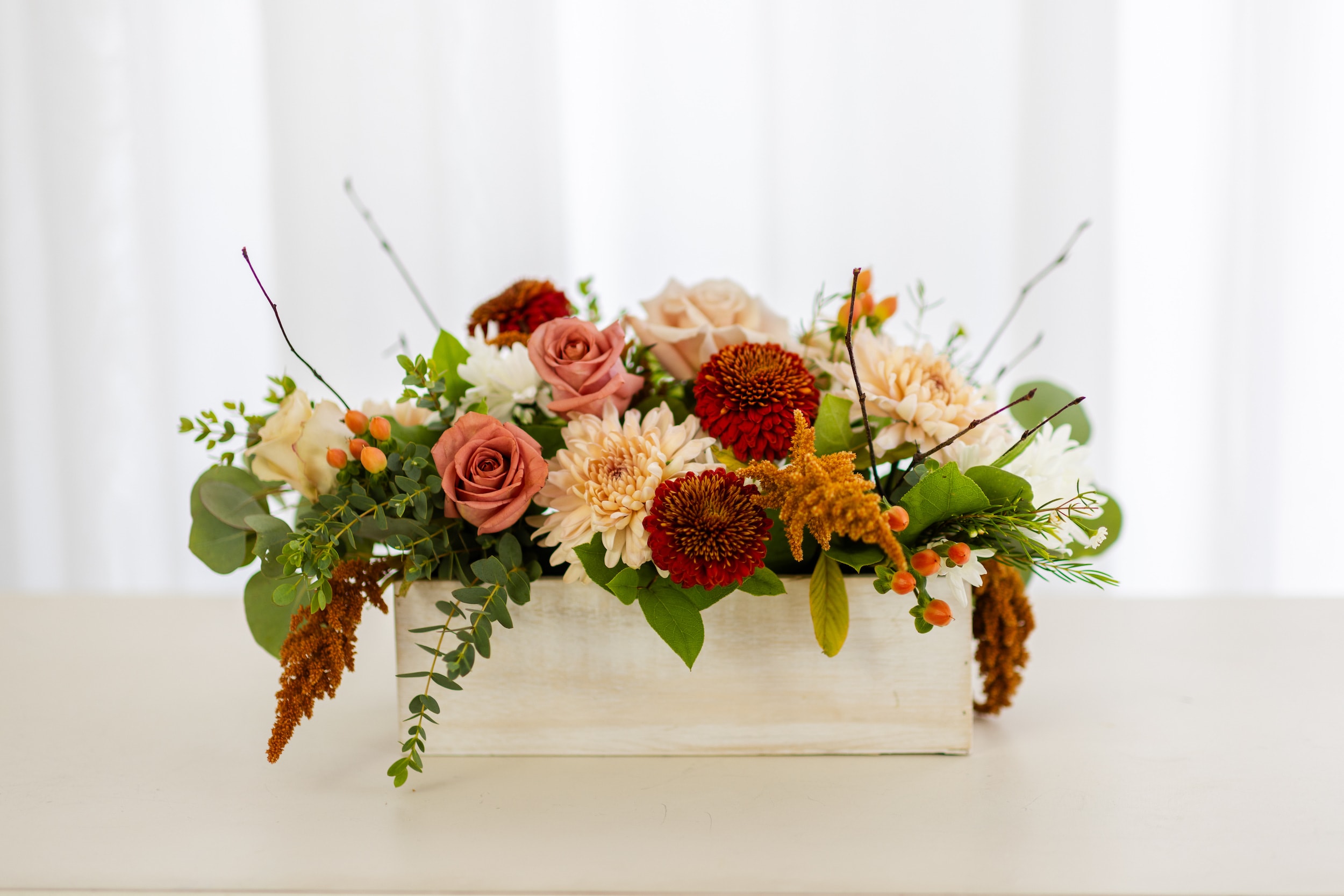 Chai Latte Collection - Medium Wood Box  - Inspired by the cozy vibes of warm fall spices, our new Chai Latte Collection brings together shades of cinnamon, mocha, and cream in a seasonal mix of mums, roses, berries, and branches—beautifully arranged in a white-washed wood box.  Perfect as a gift for a friend or loved one, or as a charming centerpiece for a fall feast.  The Chai Latte Medium Wood Box Arrangement measures approximately 14&quot; long and 6&quot; wide. 