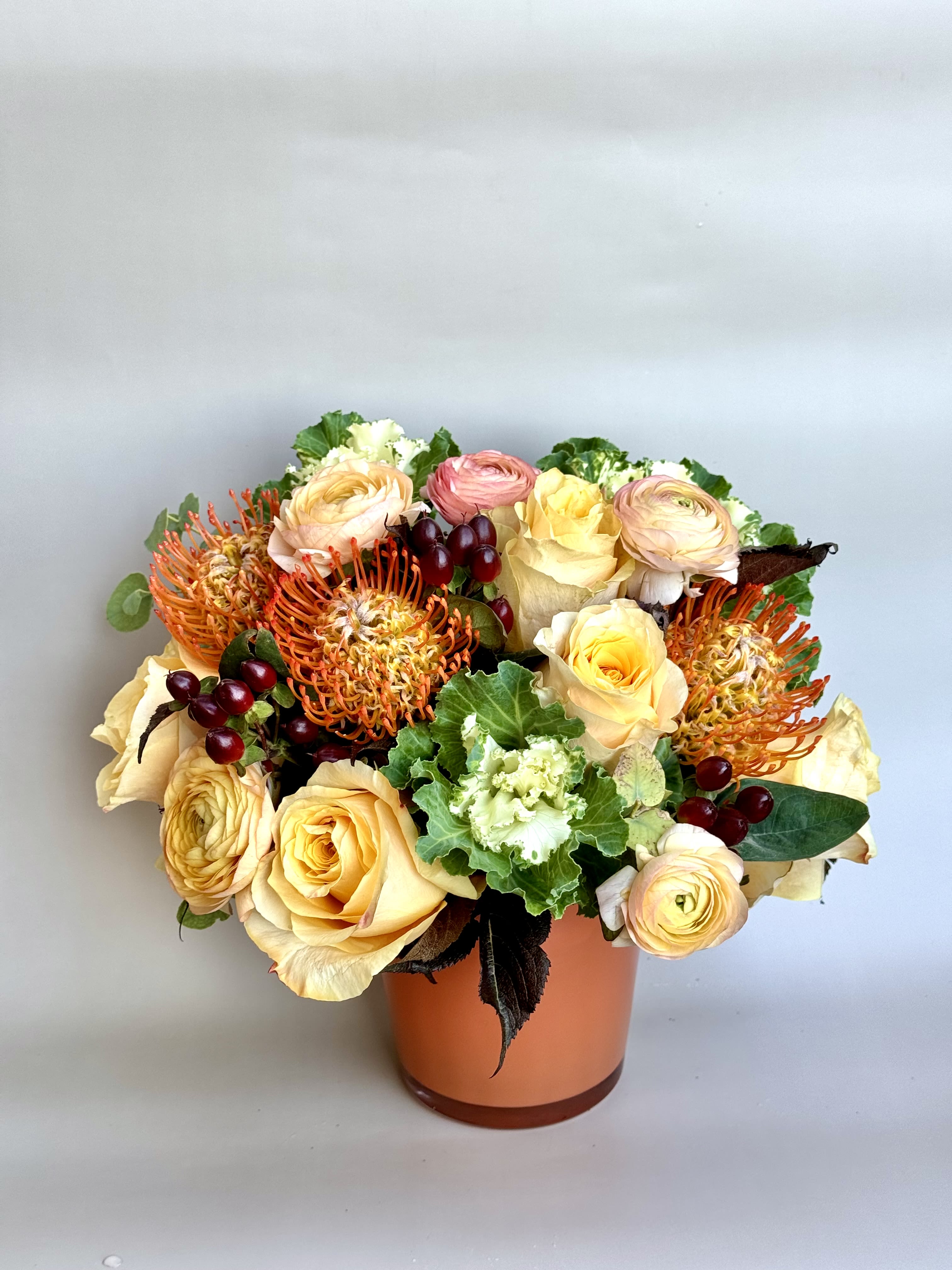 Rusty Rusty - A beautiful soft yellow perfectly combined with orange pincushions, seasonal kale, and peach ranunculus.