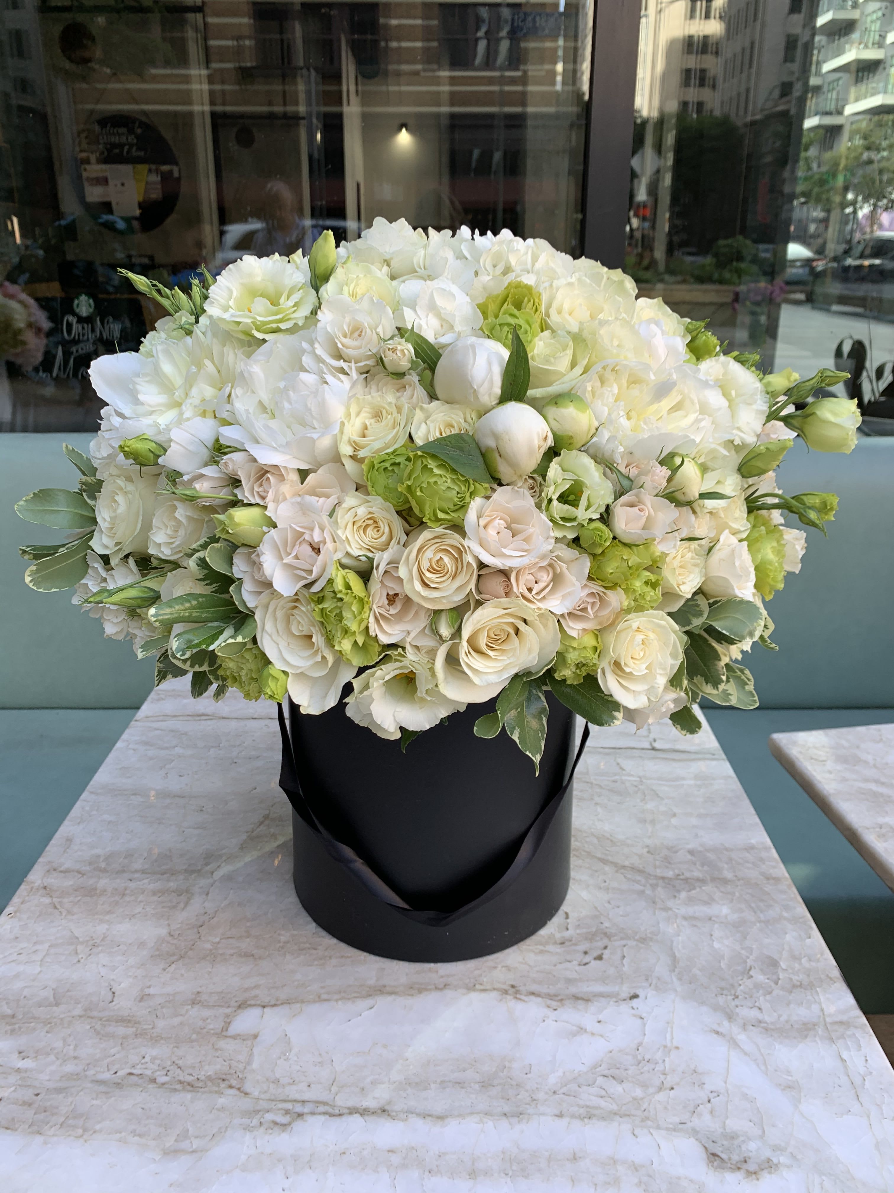 White &amp; Green flowers in Black - Introducing a truly sophisticated statement piece from your premier Los Angeles florist. This stunning luxury black box flowers arrangement offers dramatic contrast and exceptional elegance, perfect for the modern recipient.  Our expert designers have curated a lush, high-domed composition featuring premium white and green flowers—including elegant white peonies (or similar luxe seasonal blooms), classic white and blush roses, and fresh, variegated greenery accents. The striking white-and-green palette against the sleek, modern matte black box makes this the ultimate luxury gift.  Ideal for corporate clients, sophisticated interior decor, or as a high-end gift for anniversaries, birthdays, or condolences. We guarantee the highest quality and the freshest blooms for every order.  We provide fast and reliable LA flower delivery across Hollywood, Beverly Hills, and the Greater Los Angeles area. Order this breathtaking white and green arrangement today for swift fresh flowers LA service!