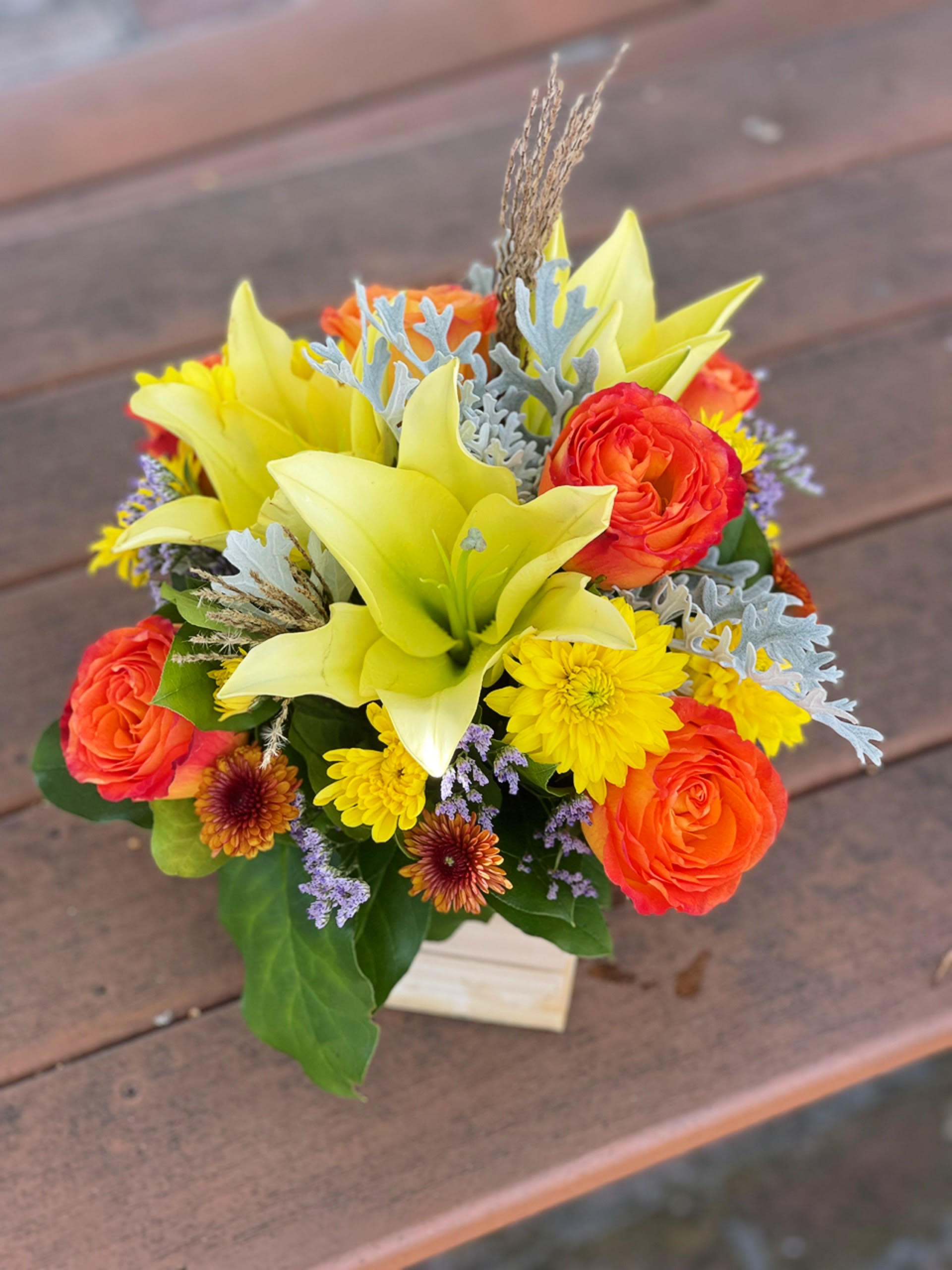 Sun Day Sun Day - - 2 Stems Yellow Lilies - 6 Orange Roses - 3 Stems Yellow Cushions - Dusty Miller - Greenery - 5 Inches Wooden Box