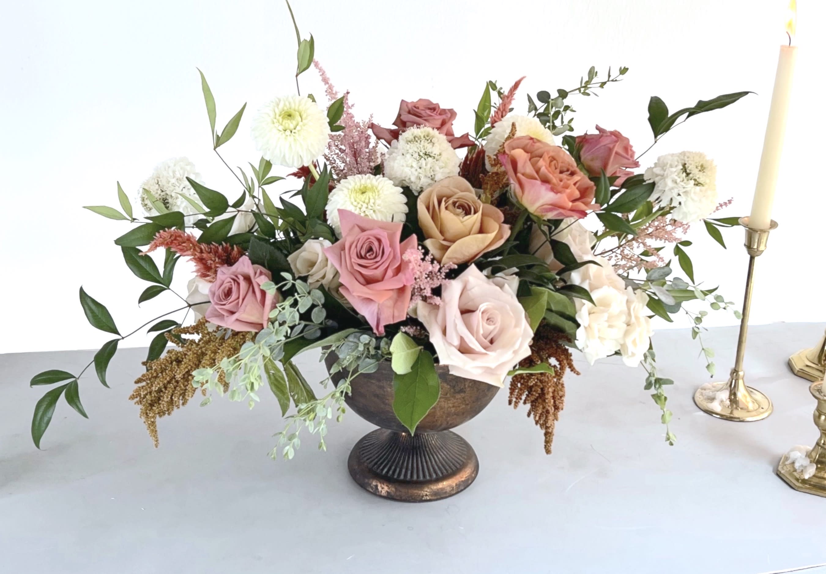 Chai Tea Collection - Compote  - Shades of cream, champagne and white stirred up with the warm colors of cinnamon, nutmeg and pepper berry all nestled in an aged bronze compote dish. New varieties of roses complete with Scabiosa, Dahlias, Eucalyptus, Celosia and Amaranthus round out this design. The ideal gift for an autumn birthday or to give thanks -  or as a lovely treat on your Thanksgiving table. Arrangement is approximately 16&quot; wide and 10&quot; high. 