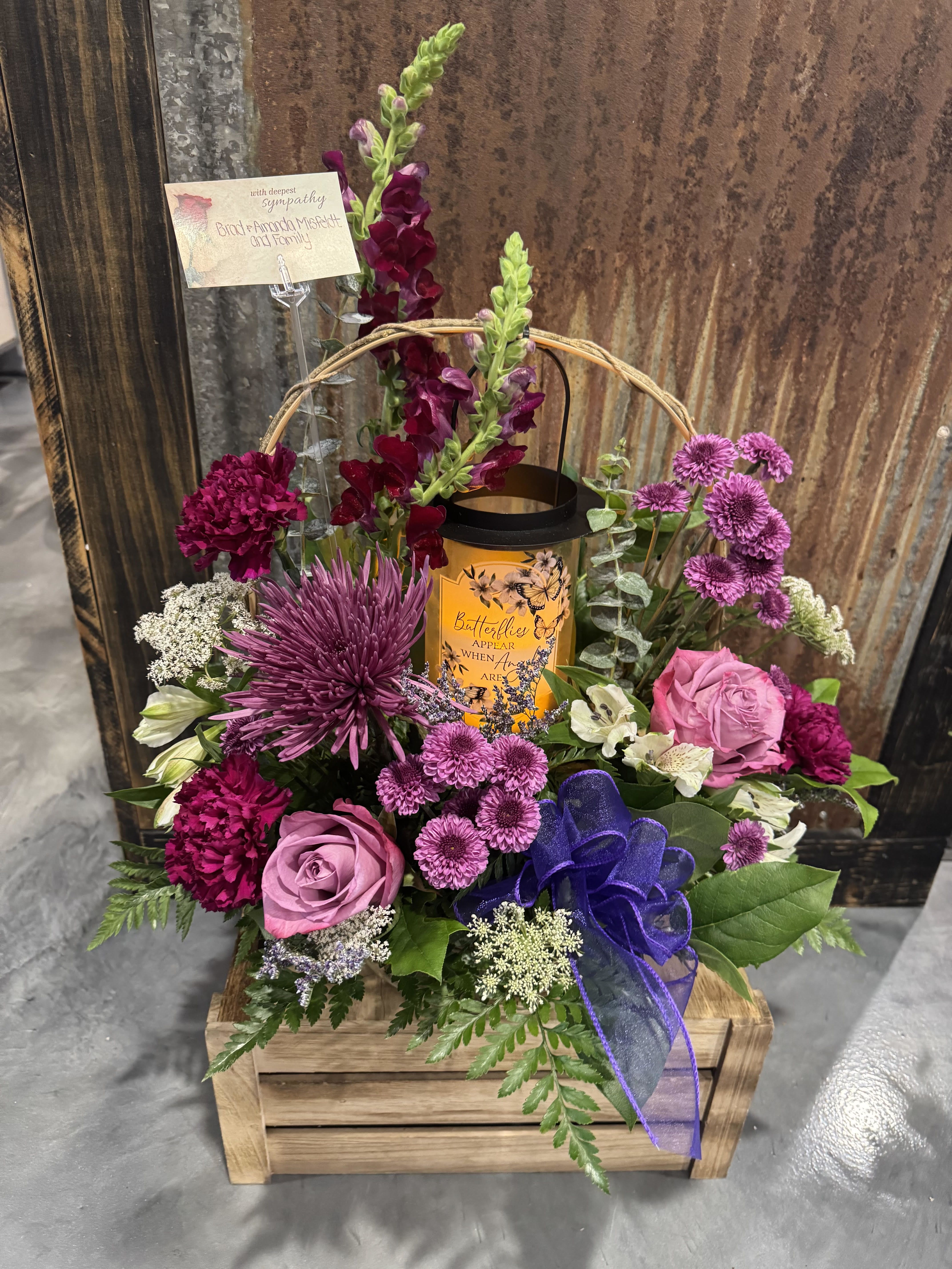 Purple Keepsake Lantern  - An assortment of Purple Flowers arranged in a basket around a Candle Light Lantern in a basket 