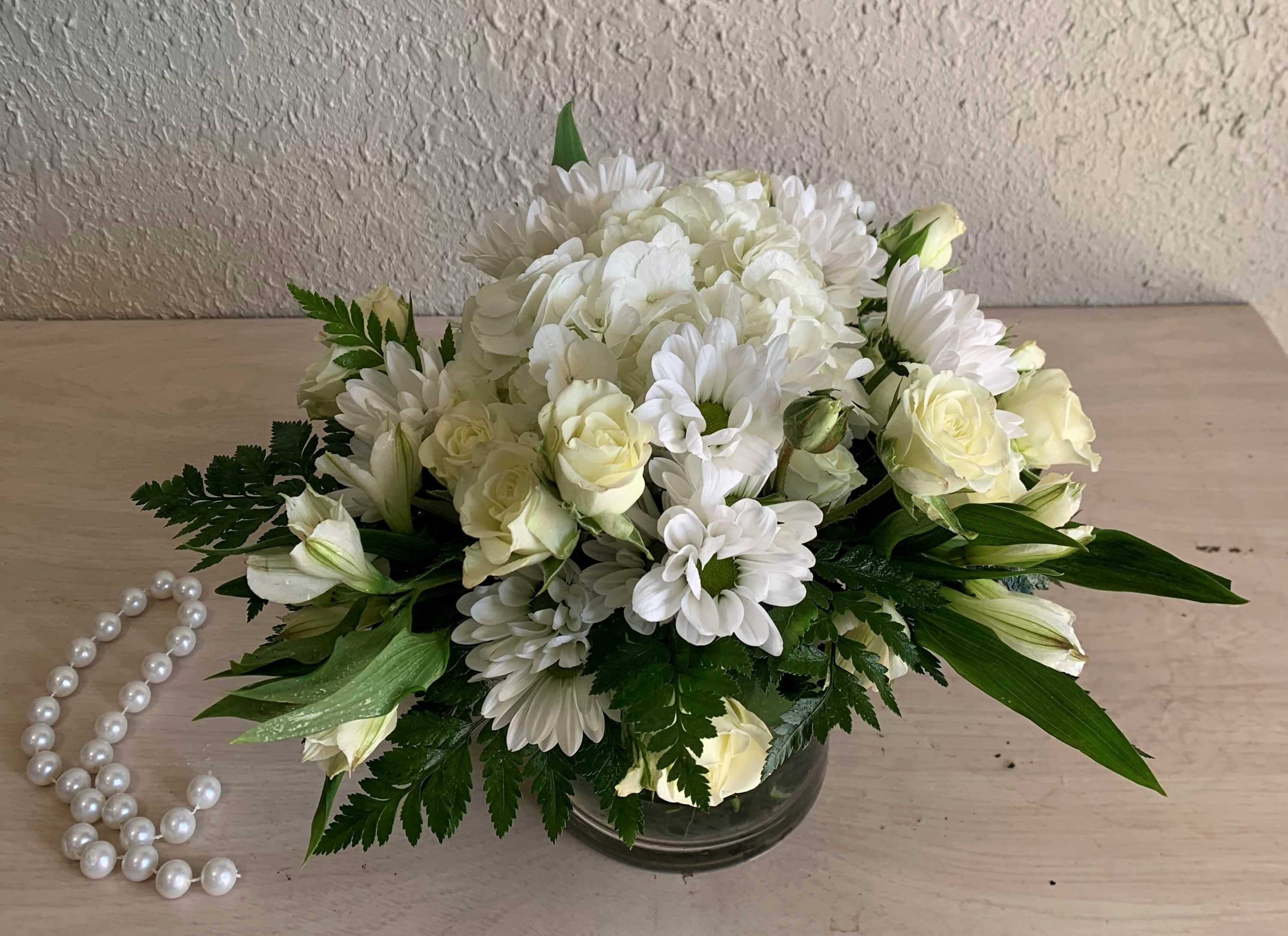 Farewell Friend (DL) - Introducing the &quot;Farewell Friend&quot; funeral flower arrangement, a loving tribute to honor and remember a dear friend. This beautiful arrangement features a delicate blend of daisies, mini spray roses, hydrangea, and alstroemeria, all in a serene and pure white color. Enhanced with premium greenery, this arrangement offers a touch of natural elegance and tranquility.  