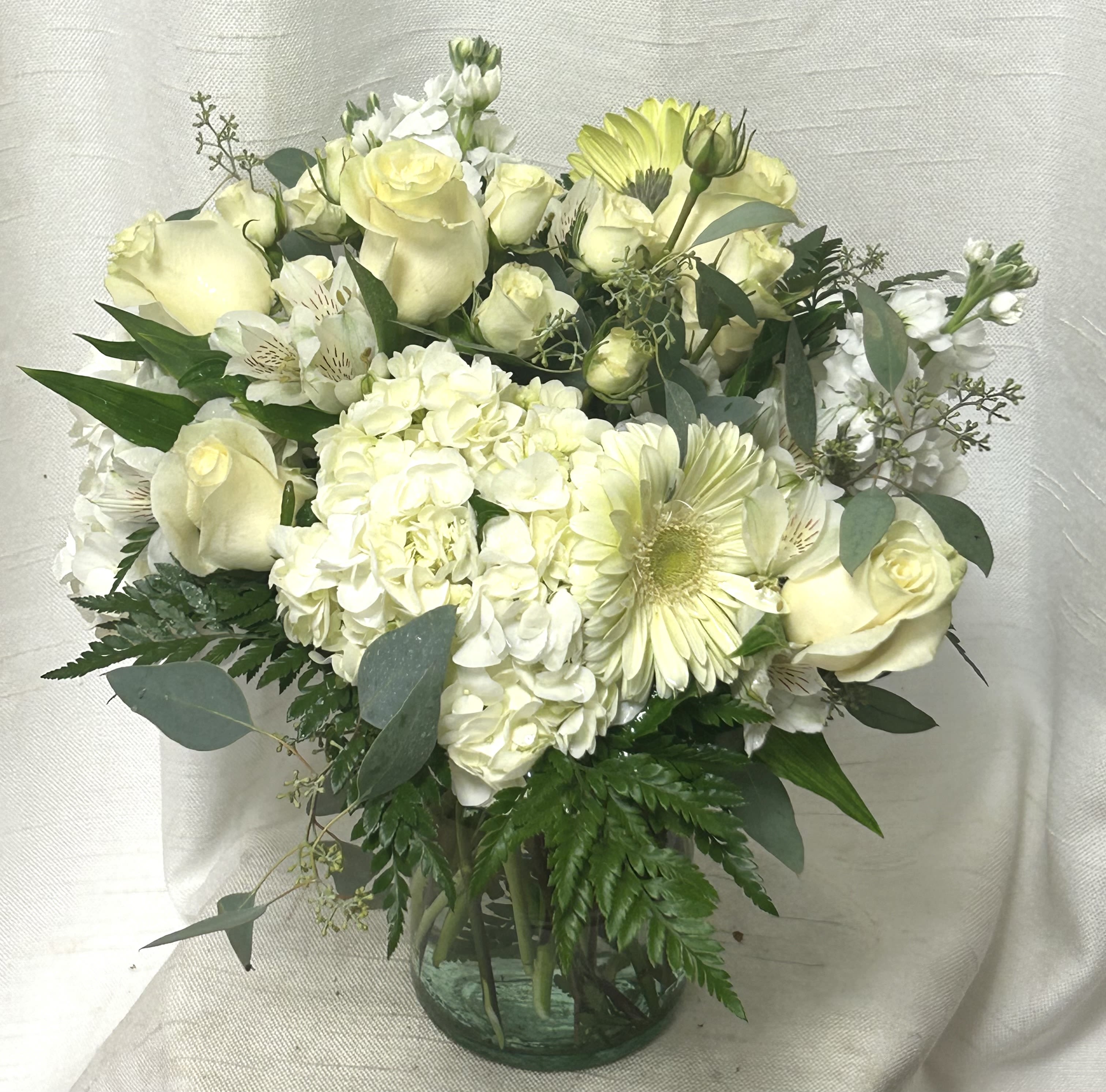 Moonlight (DL) - Step into the serene glow of the night with our &quot;Moonlight&quot; floral arrangement, a stunning bouquet inspired by the ethereal beauty of a moonlit garden. This exquisite ensemble features a harmonious blend of pristine white hydrangea, delicate white alstroemeria, elegant white roses, and cheerful white gerbera daisies, evoking a sense of peace and serenity under the luminous veil of the moon.