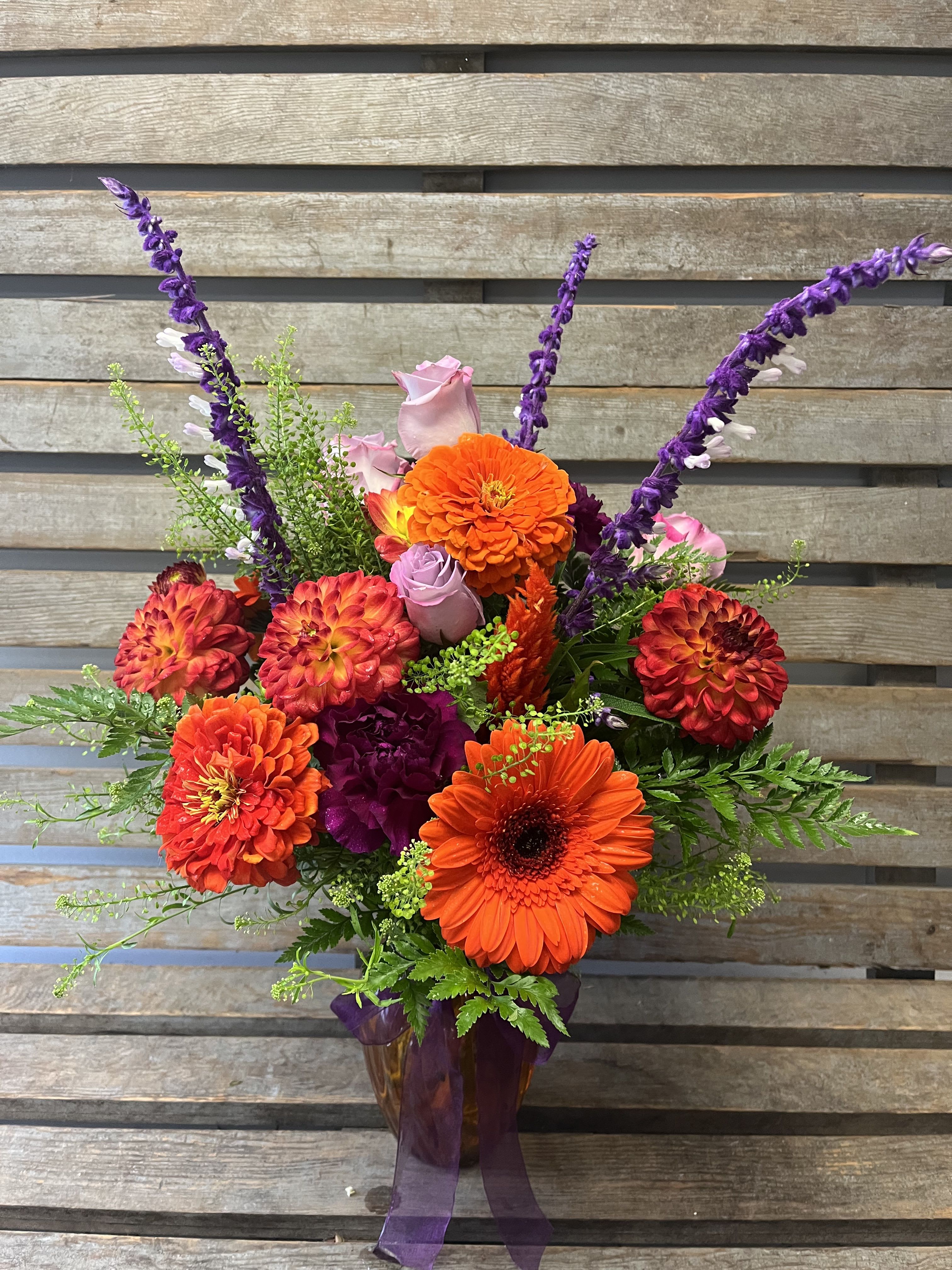 Fall vibes  Fall vibes  - Designer’s Choice of all purple & orange flowers arranged in a purple or orange glass vase. Accented  with complementary ribbon around the vase. Photo shown is the upgraded version.