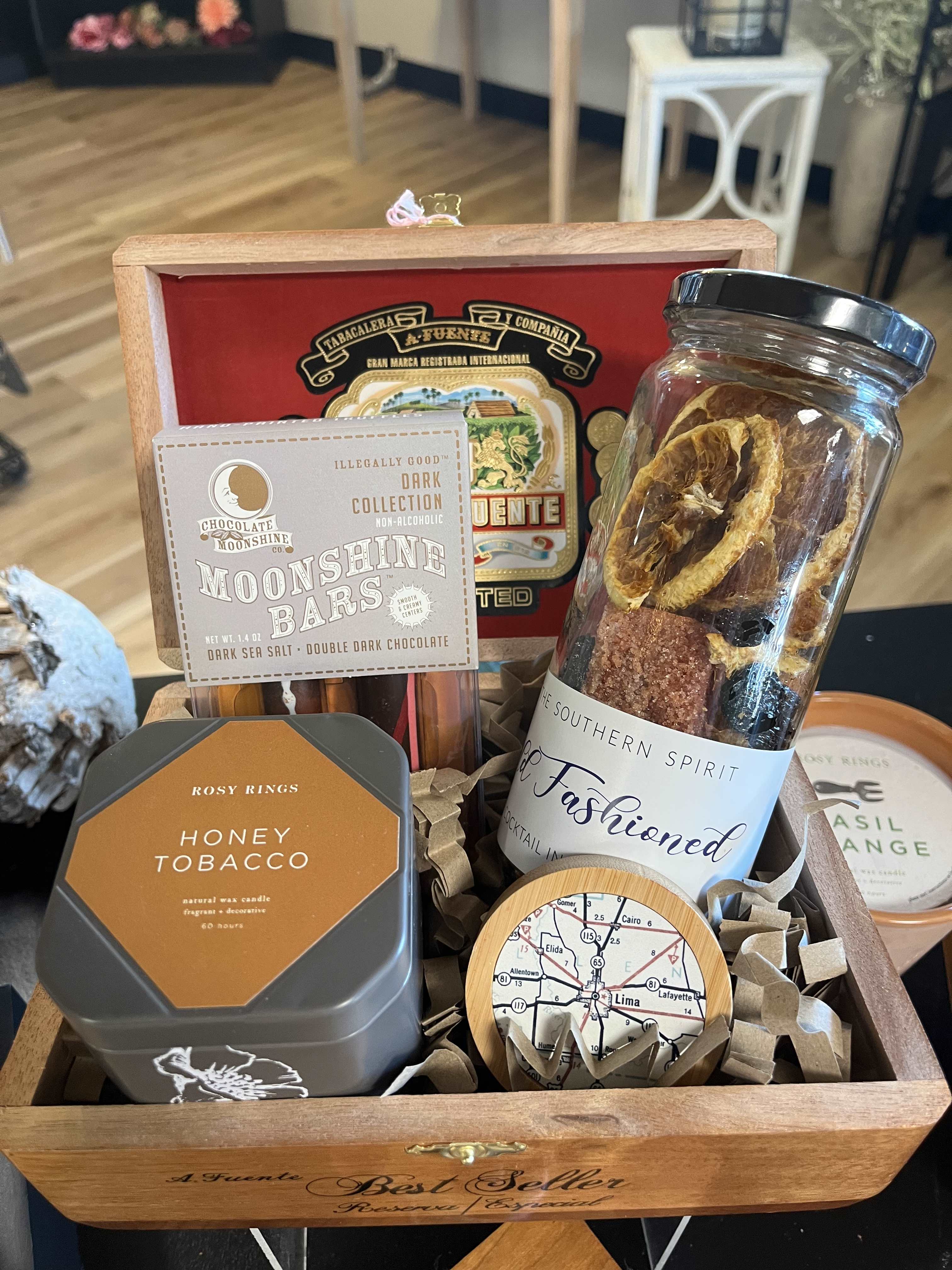 The Perfect Guy Gift - Cigar box filled with Debrand Fine Chocolates, Old Fashion Drink Mixer, Honey Tobacco Tin Candle, Celebrate Lima Bottle Opener/Magnet, and Wooden Puzzle Coasters that turn into a trivet.  Boxes will vary in price and based on availability, so substitutions may be necessary.  