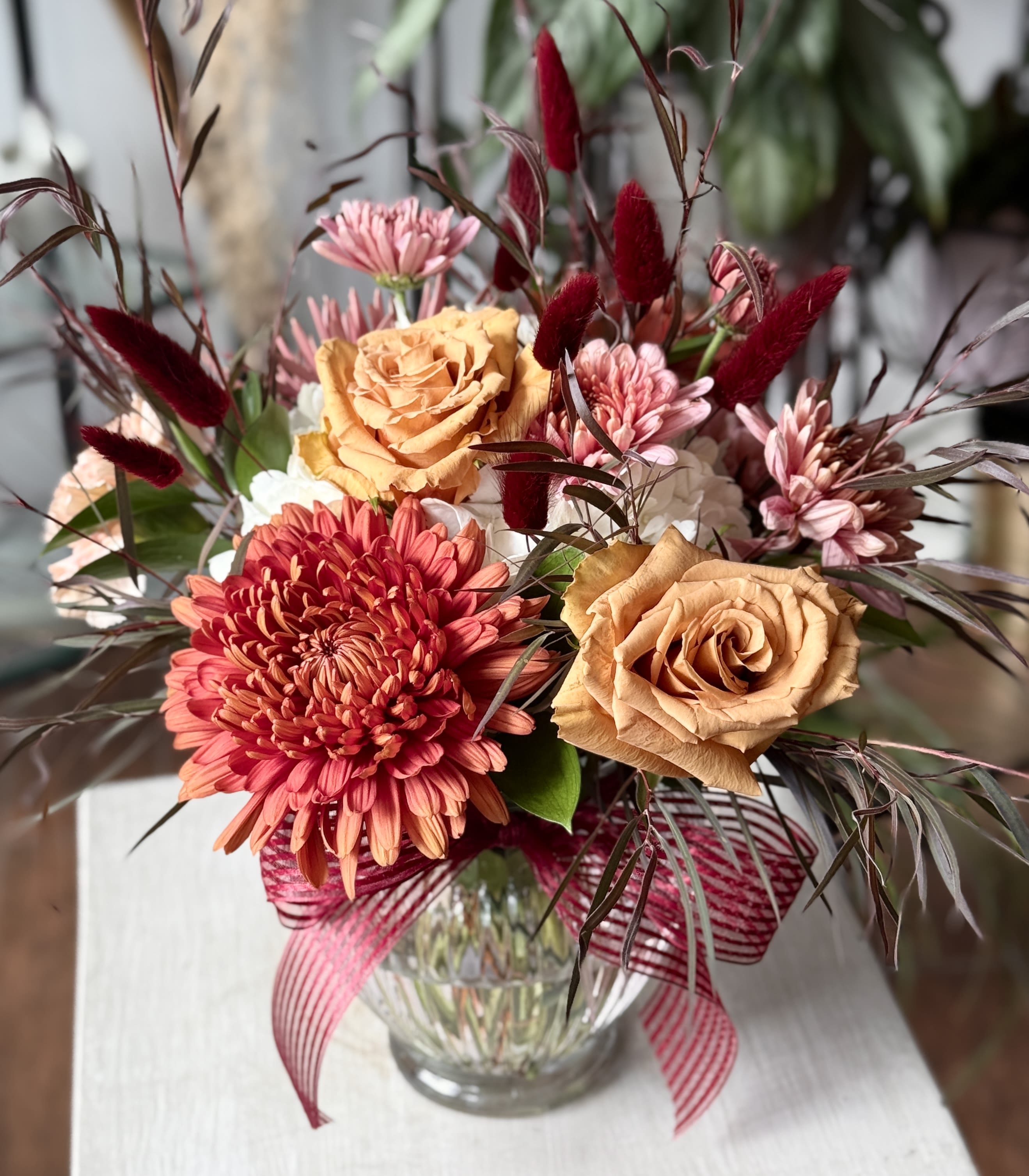 Daria Daria - Autumnal fresh flower arrangement in a clear glass vase.