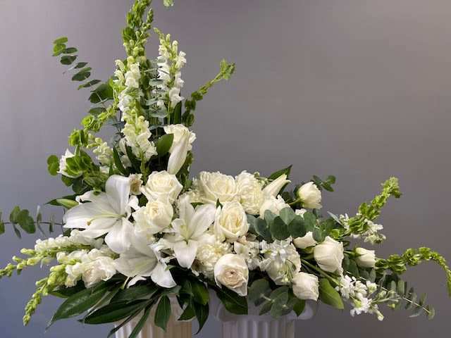 REFLECTIONS REFLECTIONS - This stunning L shaped Urn Swag is majestic looking designed with white Lilies, Roses, Snapdragons, and Eucalyptus. This will be a beautiful tribute to your loved one.