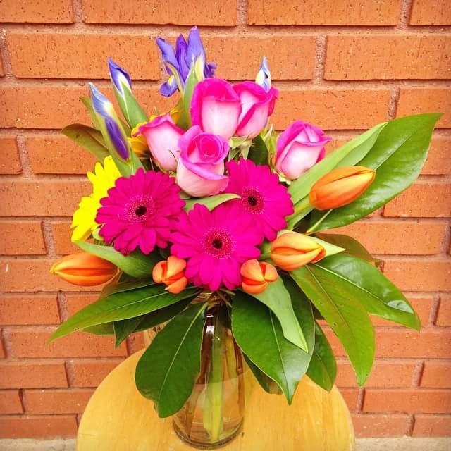 I Dream of your Tulips I Dream of your Tulips - This brilliant colored arrangement contains hot pink gerbera daisies, yellow gerbera daisies, Pink roses, orange tulips, blue iris, with magnolia leaves in a clear glass