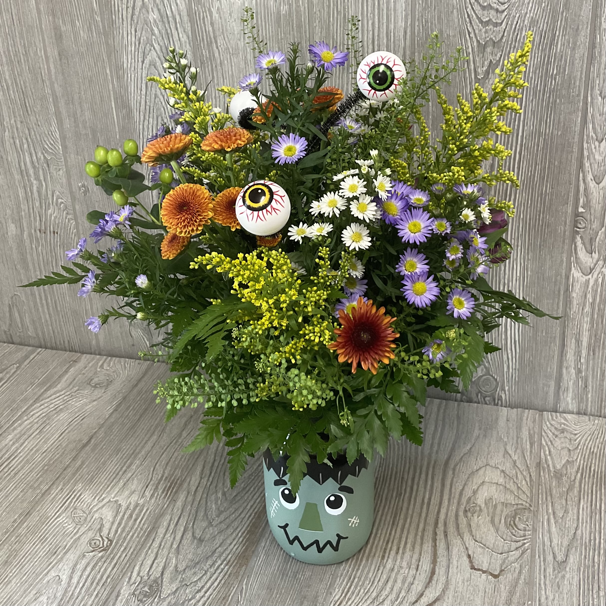 Frankenstein Wildflower - Arranged in a keepsake Frankenstein glass jar with spooky Halloween inclusions. Unique wildflower arrangement designed to look like the flowers were fresh picked along the way. Each one is uniquely made making it to where no two are alike.