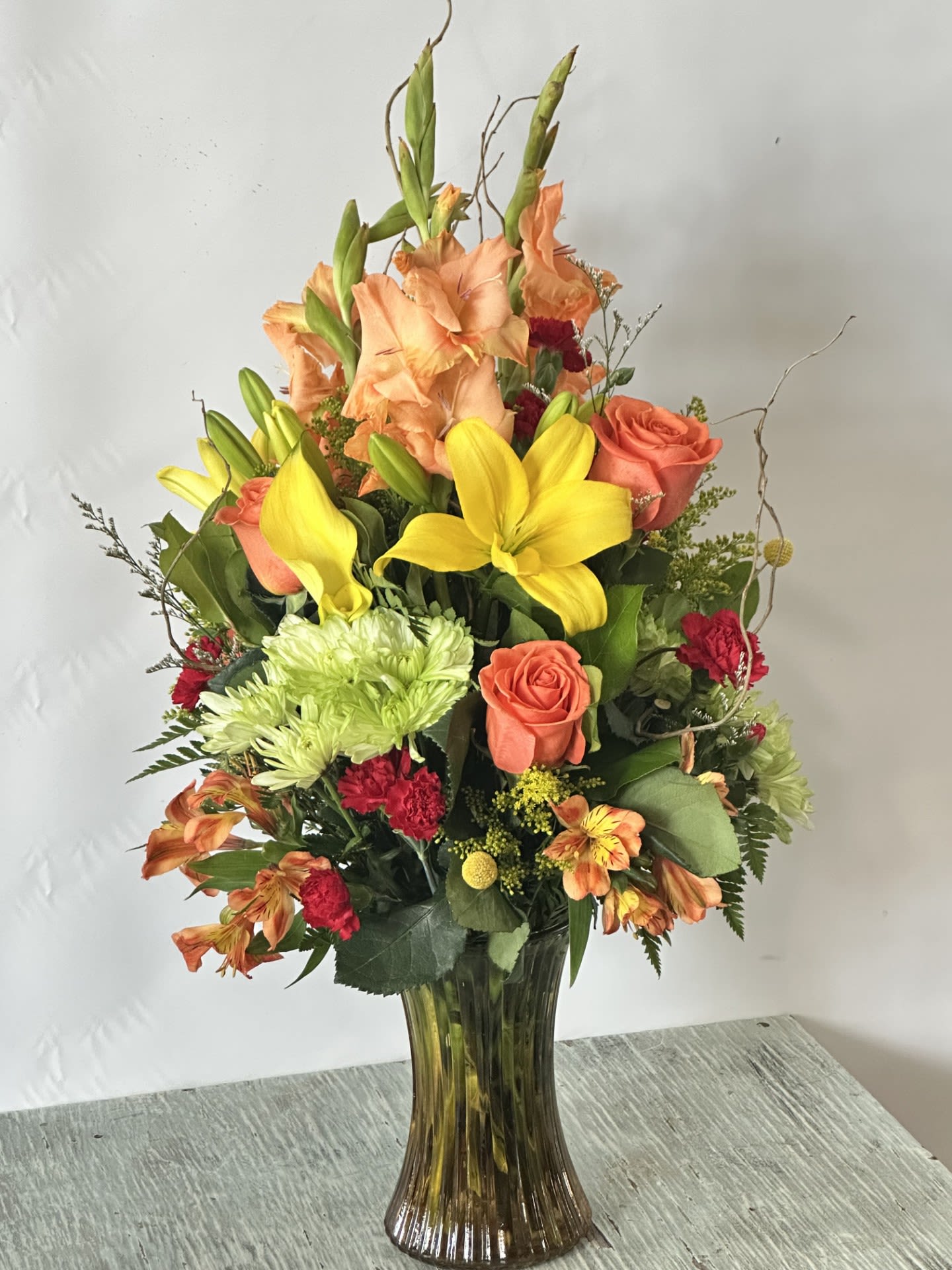 Autumn #5 Autumn #5 - Fall color arrangement designed in a translucent ribbed hourglass vase. Vase comes in ombre colors of yellow and brown. SAME DAY DELIVERY Please keep in mind we will try our best to make arrangement as similar as possible based on availability if a flower must be substituted we will keep arrangement within the same color scheme.