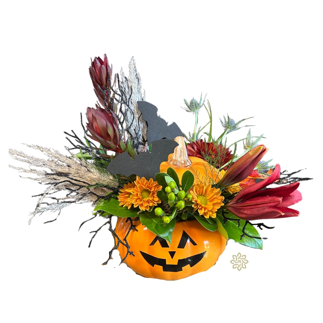 Spellbound Pumpkin Bouquet Spellbound Pumpkin Bouquet - Welcome the spirit of Halloween into your home with our spellbinding fall pumpkin bouquet. This captivating floral arrangement is a masterful blend of textures and vibrant fall colors, designed to set the perfect festive ambiance. Nestled within a charming ceramic orange jack-o-lantern container, this bouquet is sure to be the highlight of your Halloween decor.