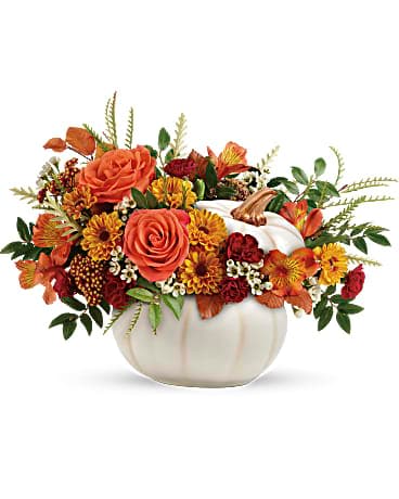 Teleflora's Enchanted Harvest Bouquet - Bursting from an enchanting white ceramic pumpkin, this fabulous fall mix of roses and mums is a magical addition to your autumnal gatherings! Orange roses, orange alstroemeria, miniature maroon carnations, and yellow viking daisy spray chrysanthemums are accented with white waxflower, red cottage yarrow, huckleberry, grevillea, brown copper beech, and yellow preserved oak leaves. Delivered in an Enchanted Harvest Pumpkin.