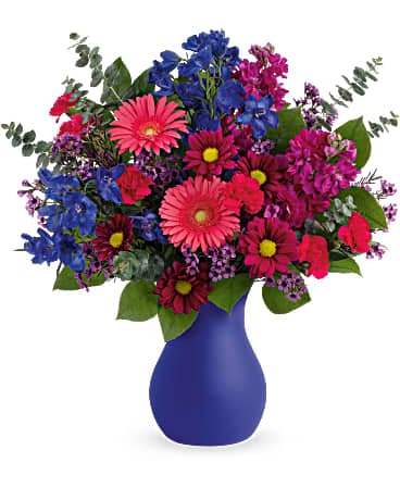 Teleflora's Jewel Tones Bouquet - Radiant as fine jewels, this bold bouquet is artistically accompanied by a frosted glass keepsake vase in the most stunning shade of cobalt. Fuchsia stock, blue delphinium, purple daisy spray chrysanthemums, lavender waxflower, miniature pink gerberas and miniature hot pink carnations are arranged with lemon leaf and spiral eucalyptus. Delivered in Teleflora's Serendipity Glass Vase.