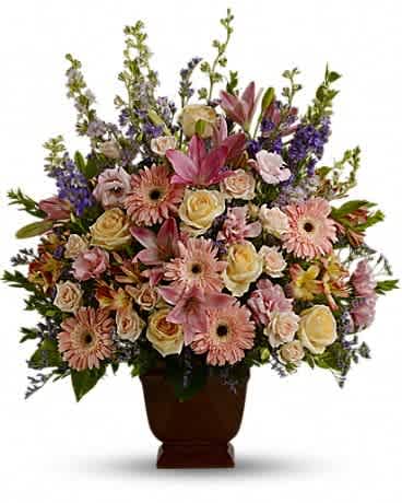 Teleflora's Loving Grace - A warm and peaceful bounty of pastel blossoms gently expresses love and respect. A gracefully composed arrangement appropriate for home or service. Fresh flowers such as peach and light pink roses, lavender and purple larkspur, pink asiatic lilies, alstroemeria, gerberas and lisianthus are set in an exclusive Noble Heritage urn.