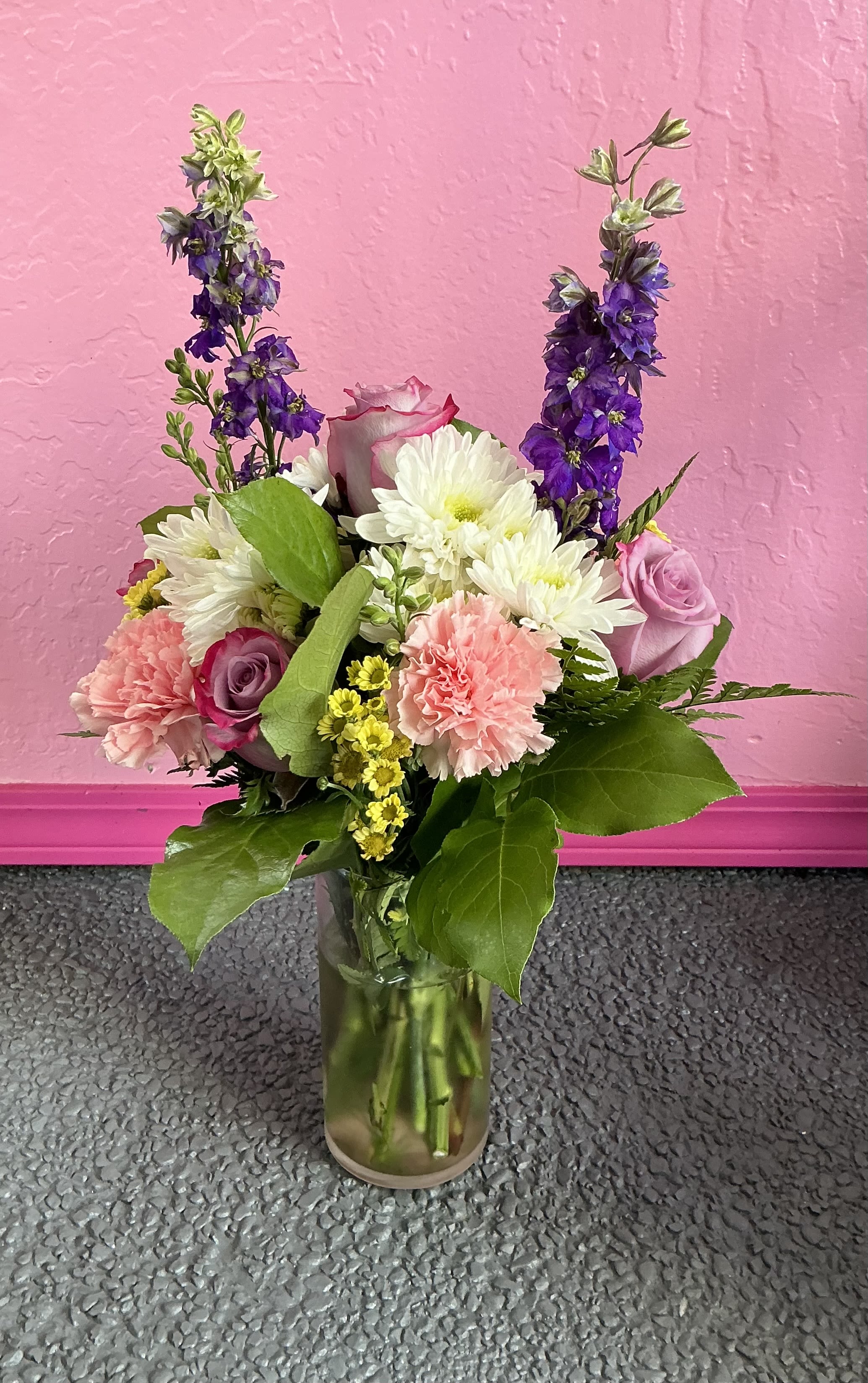 Anastasia - This sweet floral vase arrangement features 5 roses, 4 carnations, 4 micro pompon daisies, 3 cushion pompon stems, 2 stock flower stems, and some assorted greenery. Call us to make custom changes.