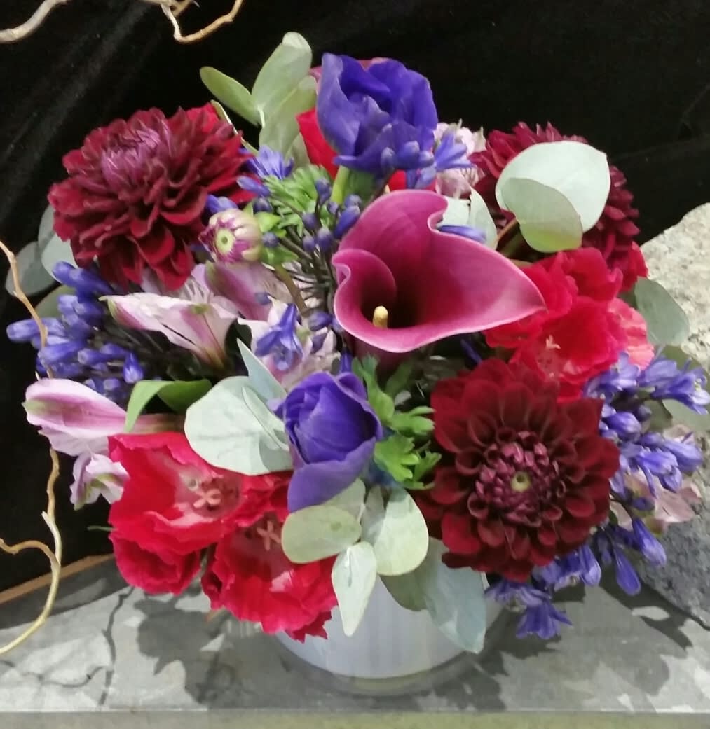 Bountiful, Beautiful, Berry Bountiful, Beautiful, Berry - The colors and flowers in this classy arrangement remind me of a summer berry harvest. Dahlias shipped direct to Crimson Petal from Holland (the best in the world), Anemones in vivid purple, and Calla Lilies in soft berry tones blend beautifully with silver greenery in a frosted cylinder vase. The colors of the flowers mimic nature's Blueberries, Raspberries, and Blackberries so abundant this time of year.