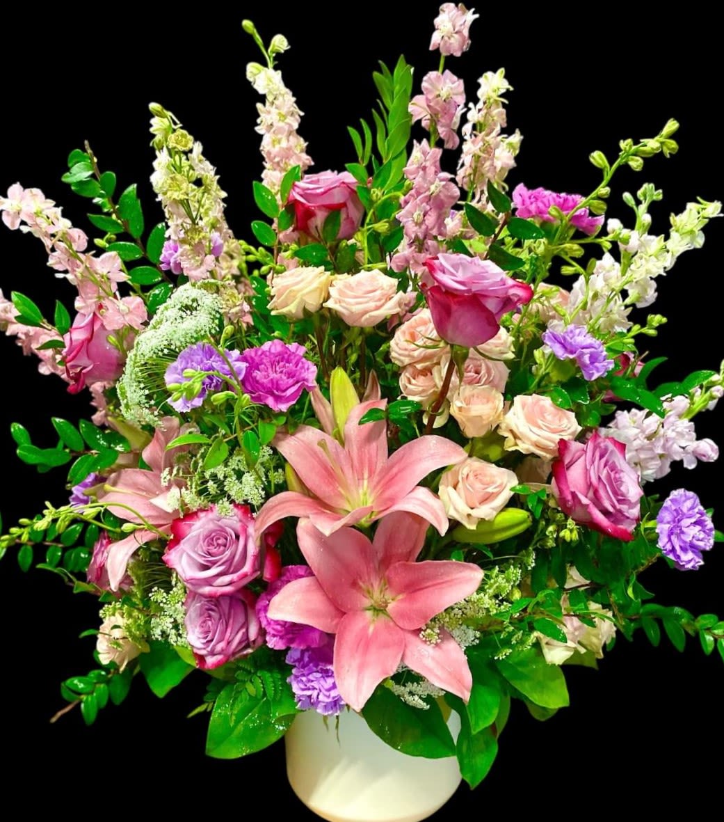 Blush Garden Bouquet Blush Garden Bouquet - This soft blush large two sided design includes a wonderful variety of lush blooms in various shades of Lavender, Pink, and accented in White. This design includes Lavender Roses, Carnations, Stock, Soft Pink Asiatic Lilies, Spray Roses, Larkspur, and Queen Anne's Lace; All set on a decorative ceramic container. This design measures approx. 26"W x 30"H.