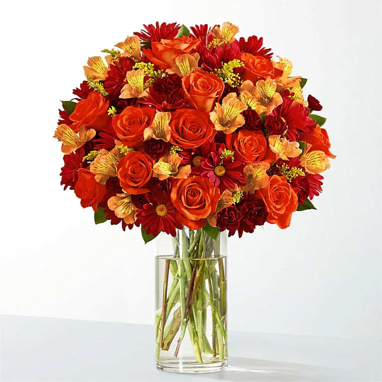 FALLING LEAVES FLOWERS  FALLING LEAVES FLOWERS  - FALLING LEAVES   Celebrate late autumn with these rich tones of orange, red, burgundy and yellow. This arrangement is the perfect end of fall delight to bring the beauty of the season inside. DETAILS  Includes approximately 35 stems of florals and greens, as well as a clear glass vase. This bouquet comes with floral food and care instructions, packed carefully within a gift box. As soon as you take your bouquet out of the box, trim the stems at an angle and place them in room temperature water with flower food. For long-lasting blooms, replace water daily and continue to trim stems.  1 dozen Orange Roses