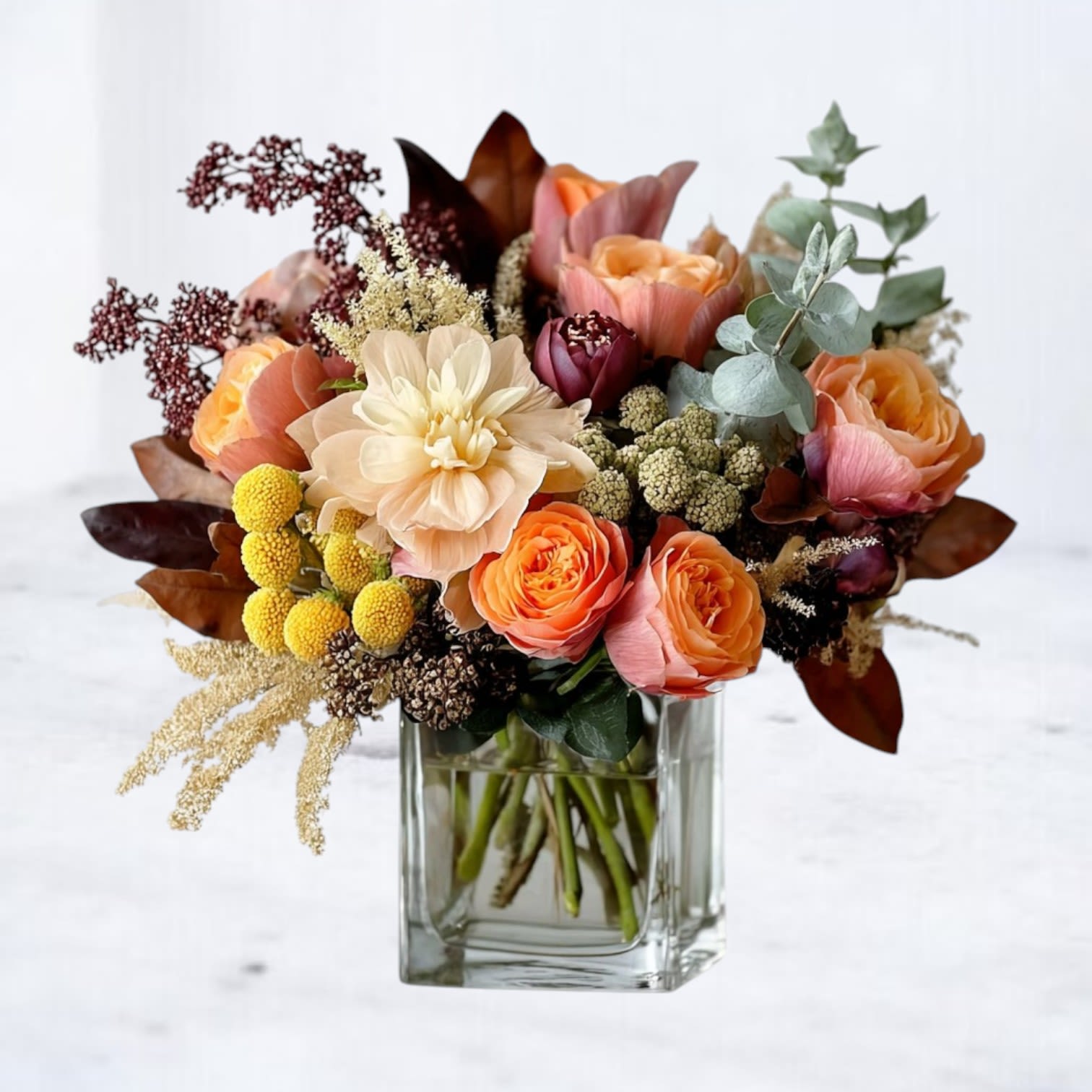 Amber Dusk Bouquet Amber Dusk Bouquet - The Amber Dusk Bouquet captures the glow of fall with a rich blend of seasonal textures and warm hues. Featuring peach garden spray roses, golden craspedia, creamy blooms, and deep burgundy accents, this design is layered with eucalyptus and rustic foliage for a modern, autumn-inspired look. Arranged in a sleek glass vase, it’s the perfect gift for birthdays, anniversaries, or as a cozy centerpiece for fall gatherings. Available for next-day flower delivery in Houston and surrounding areas, the Amber Dusk Bouquet is a sophisticated way to celebrate the season.
