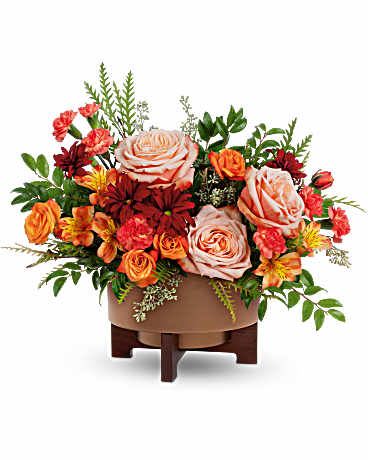 Copper Celebration Centerpiece - Celebrate the season with warmth and charm. The Copper Celebration Centerpiece captures fall's cozy glow with rich orange blooms and lush textures, beautifully arranged in a copper-finished planter with wooden stand-perfect for Thanksgiving gatherings and autumn moments. Featuring peach roses, orange spray roses, orange alstroemeria, miniature orange carnations, and red daisy spray chrysanthemums, it's accented with seeded eucalyptus, grevillea, and huckleberry. Approximately 16 1/4&quot; W x 13 1/4&quot; H.